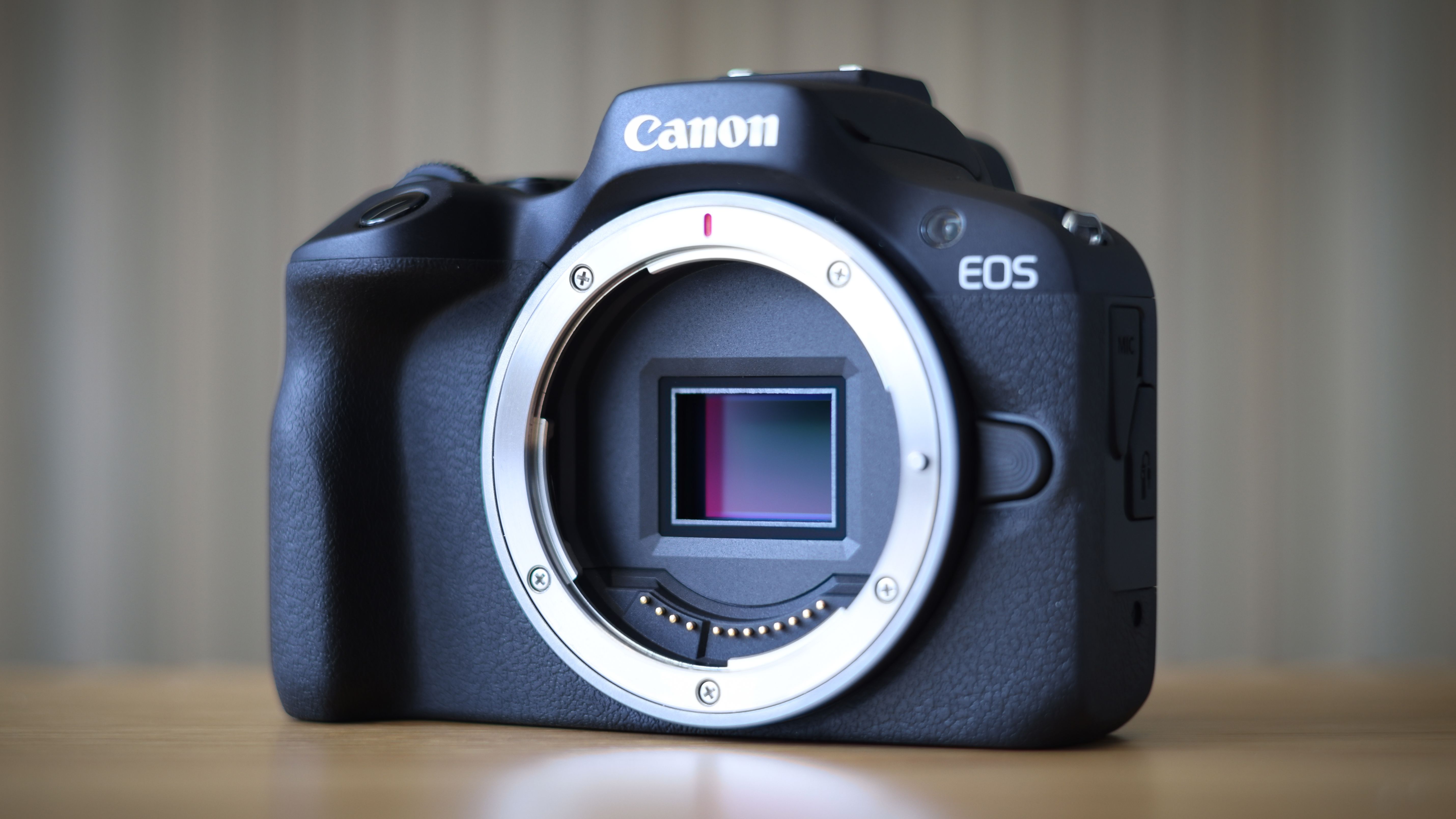 Canon EOS R100 camera on table with striped background