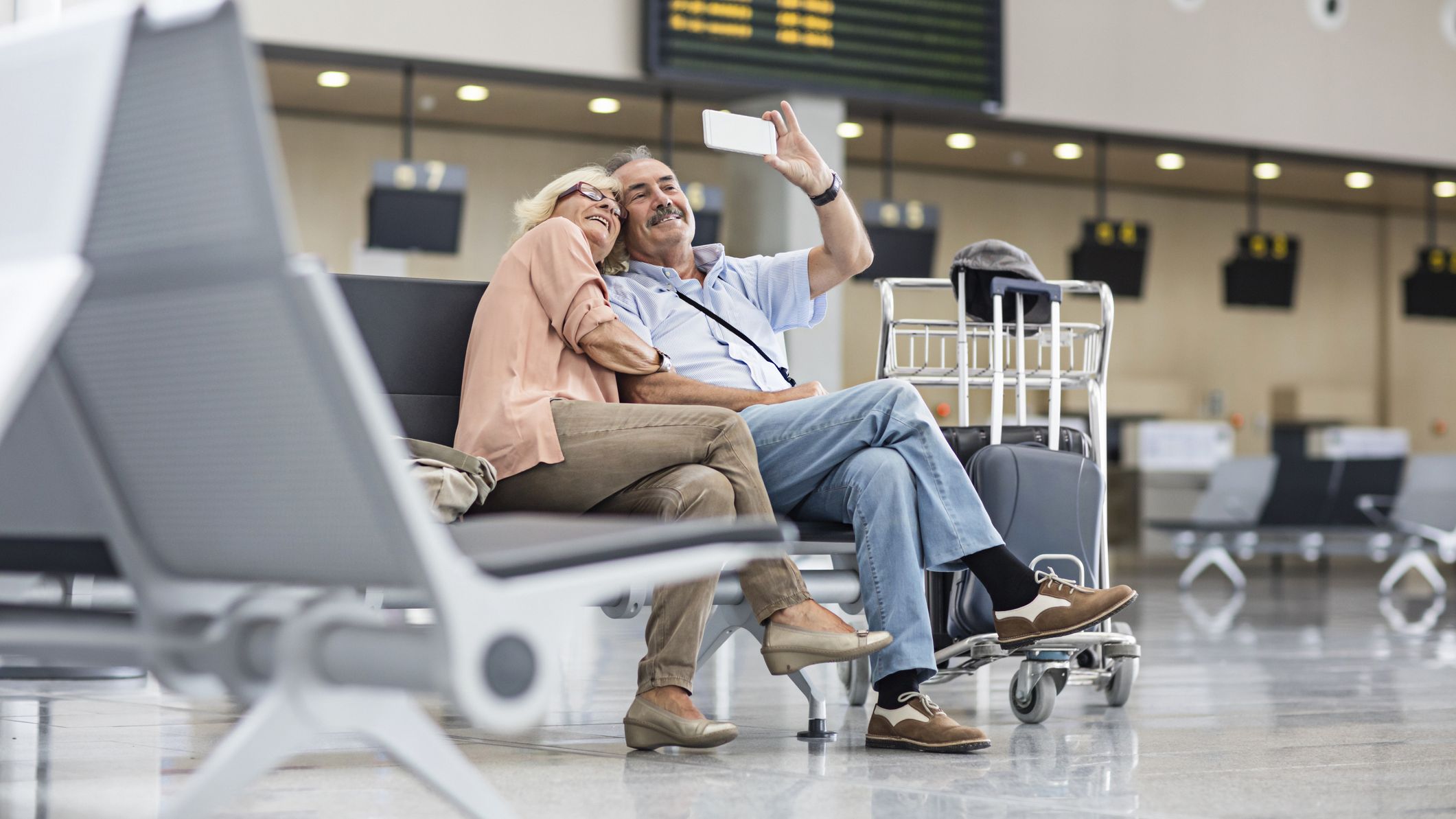 Senior Couple taking a selfie in the airport while waiting to check in at the airport for their holidays.