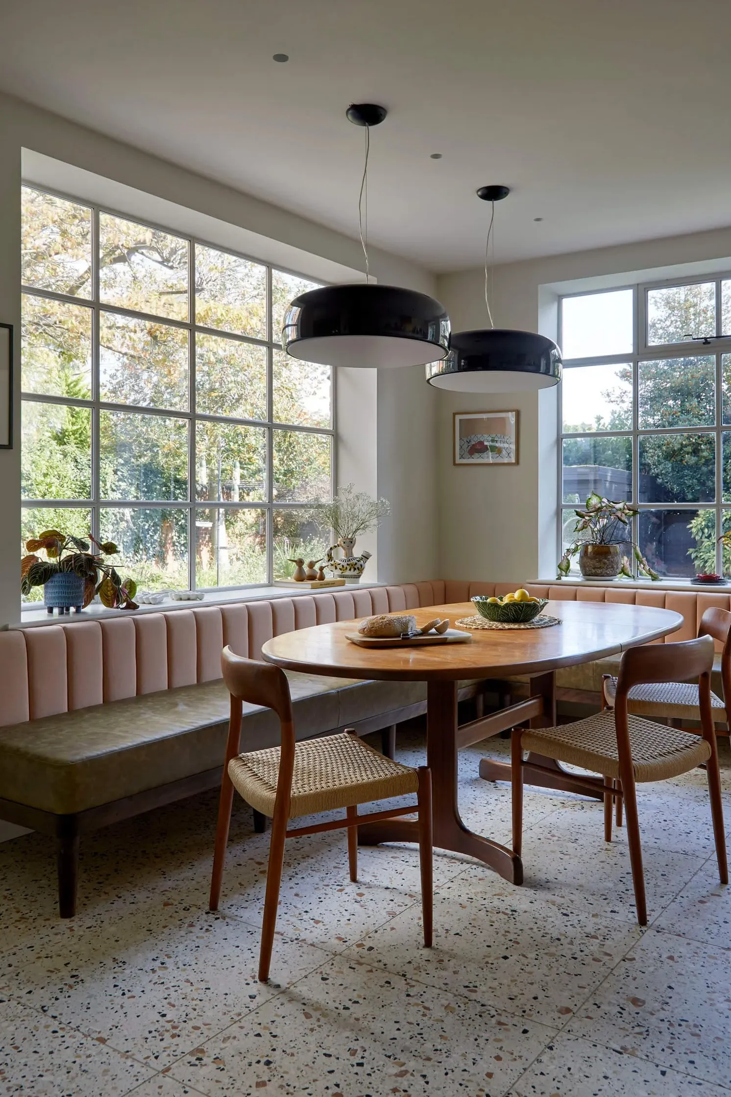 leather and fabric banquette with oval table and mid-century chairs, black pendant lights and terrazzo floor