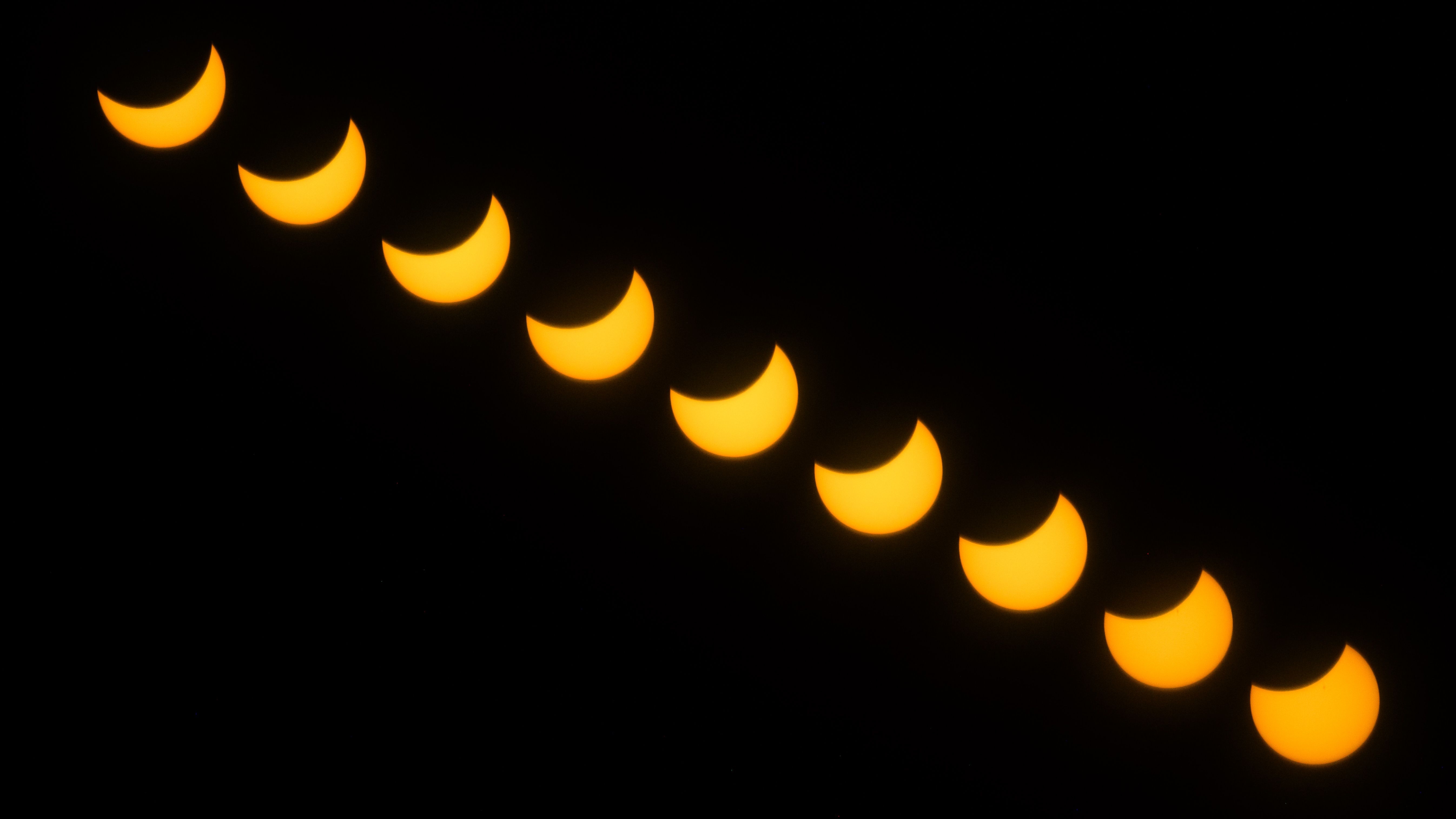 A composite view of a solar eclipse showing the moon passing off of the solar disk in a black sky.