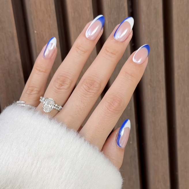 Sheer almond nails finished with curved cobalt blue French tips