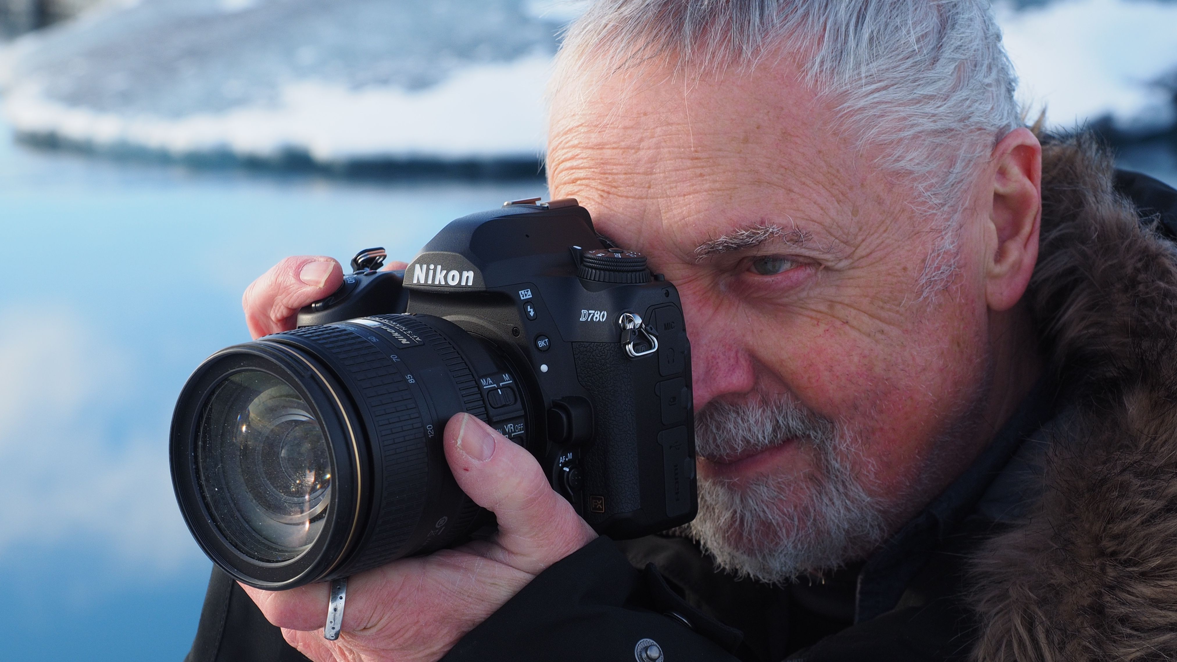 Man holding a Nikon D780 in front of an icy lake