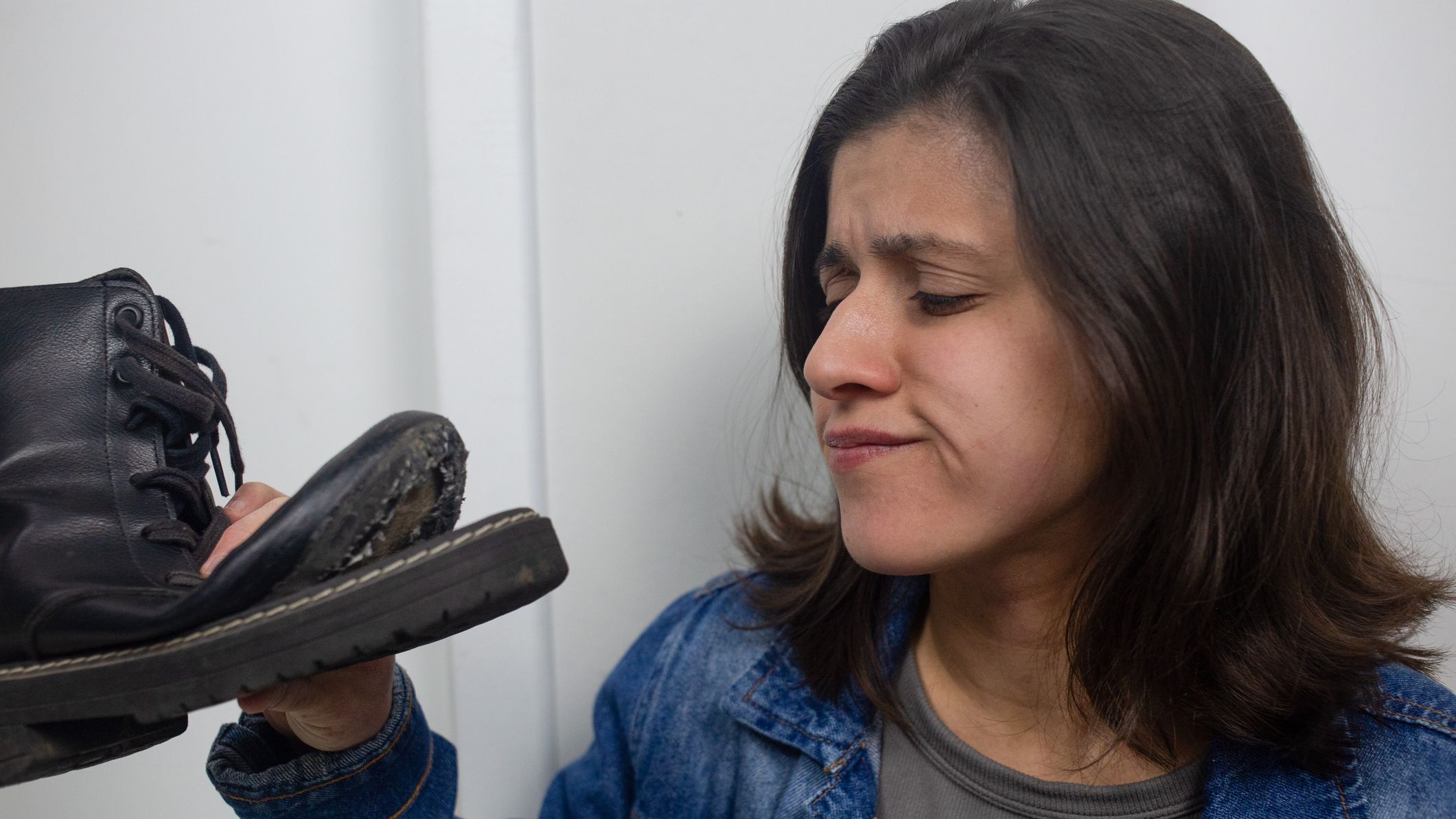A woman looking at a boot that needs to be repaired.