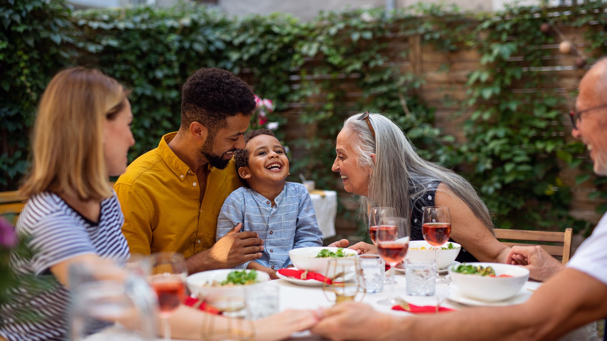 Happy multigeneration family talking and laughing at garden during birthday party.