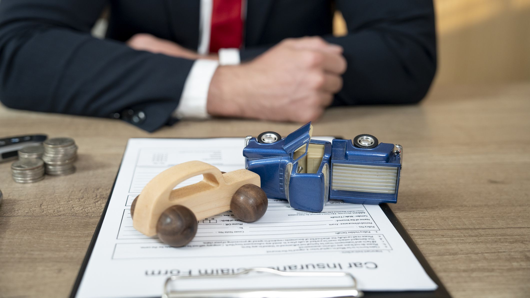 Car insurance claim documents with a small wooden car and toy truck.