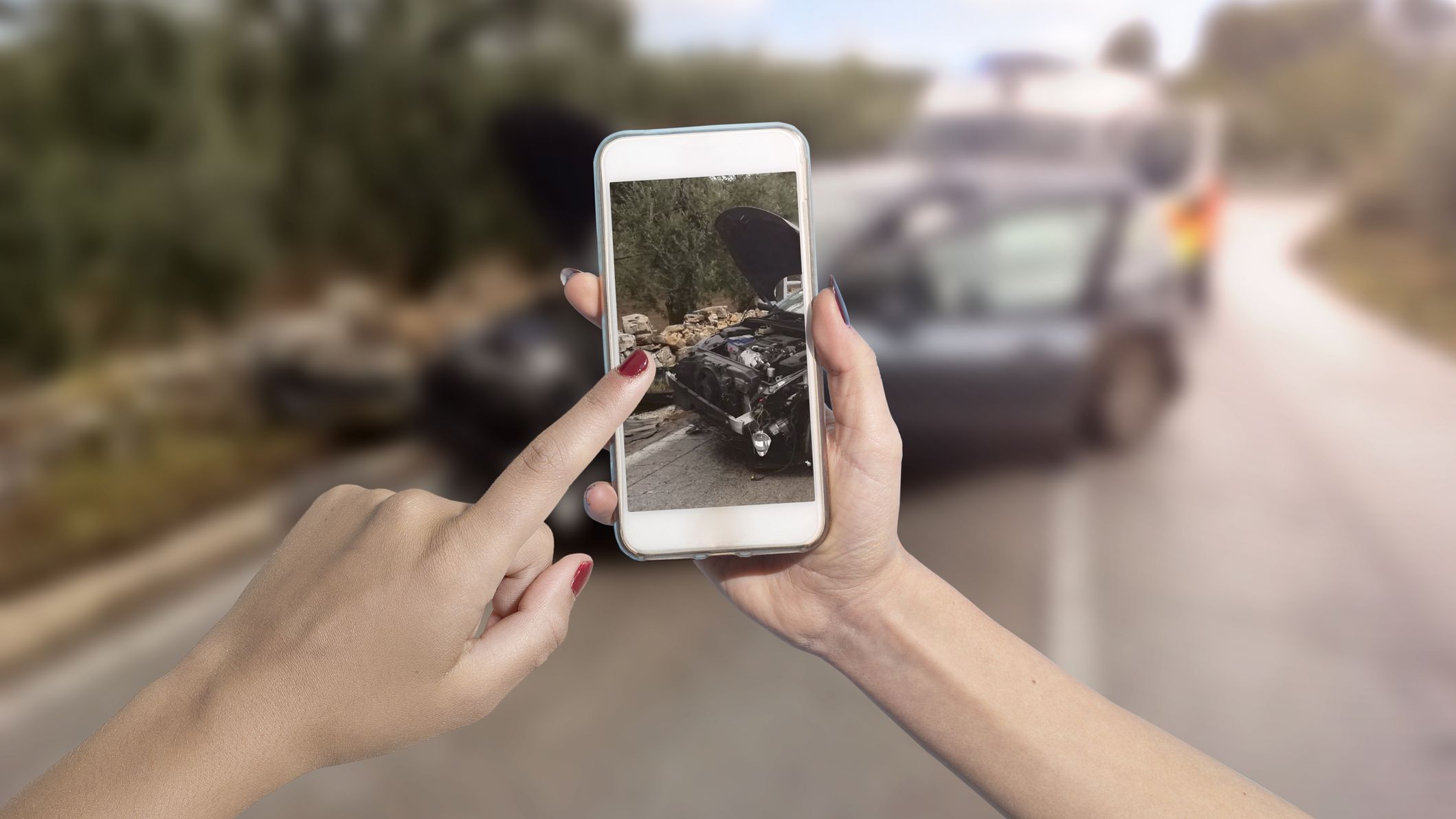 a person taking a picture on their phone of a car accident