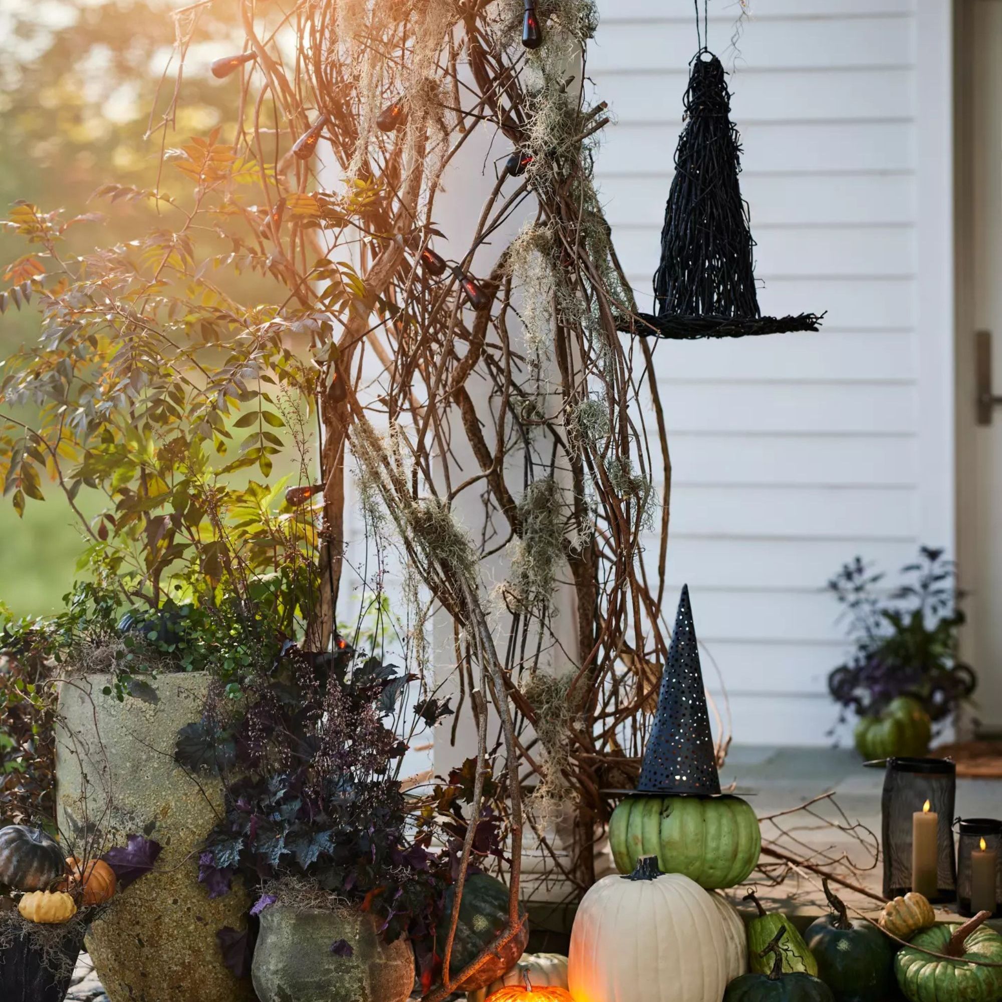 halloween porch decor with pumpkins foliage and a wicker witches hat
