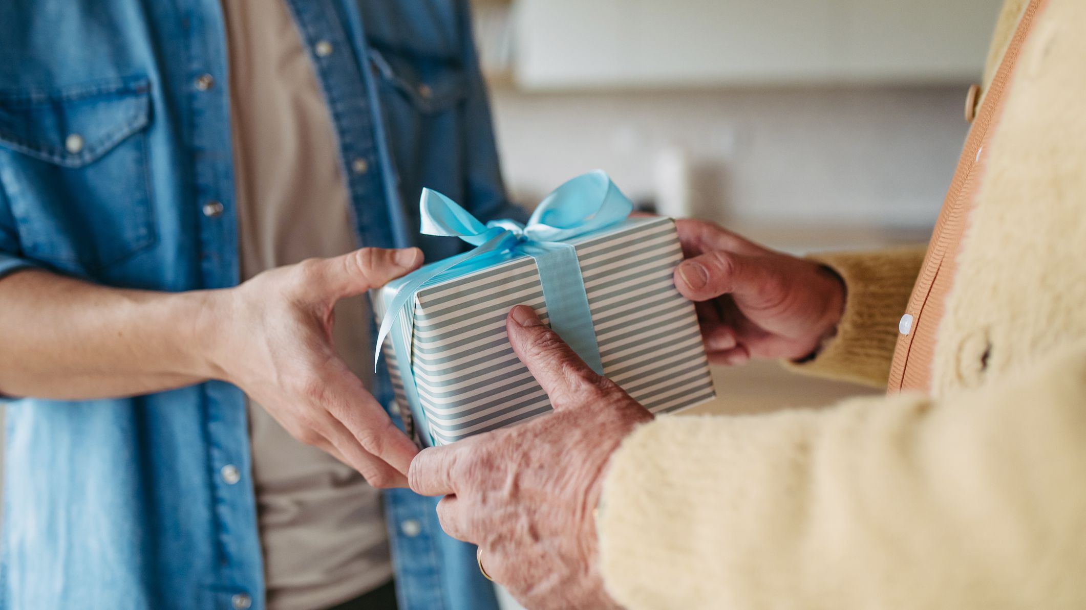 Either a son is giving a gift in a box with a bow to his father, or his father is giving his son the gift.