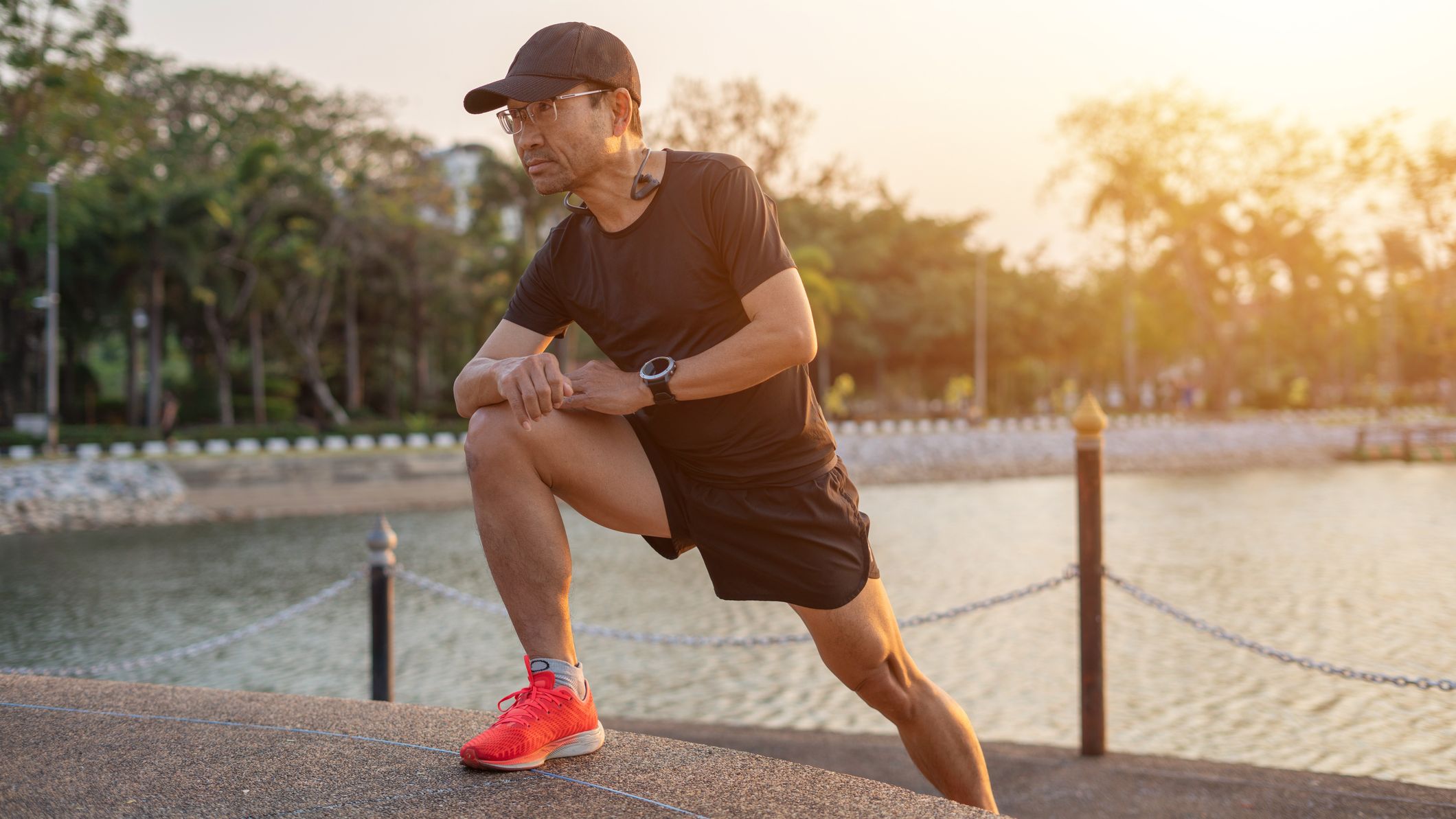 Man in running clothes stretches next to a lake