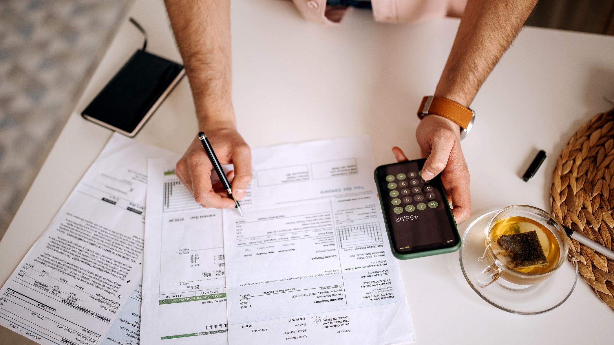 A man looking over his monthly billing statement with a calculator in hand.