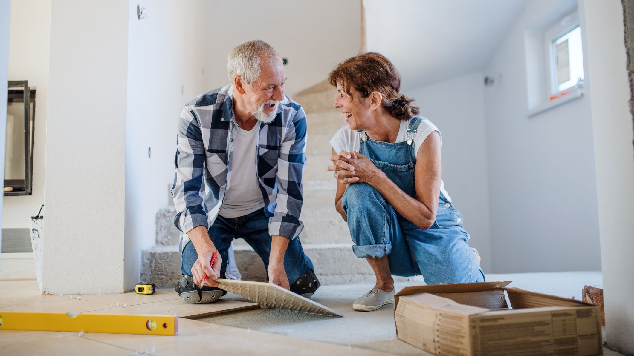 Couple laying tile floor in new home.