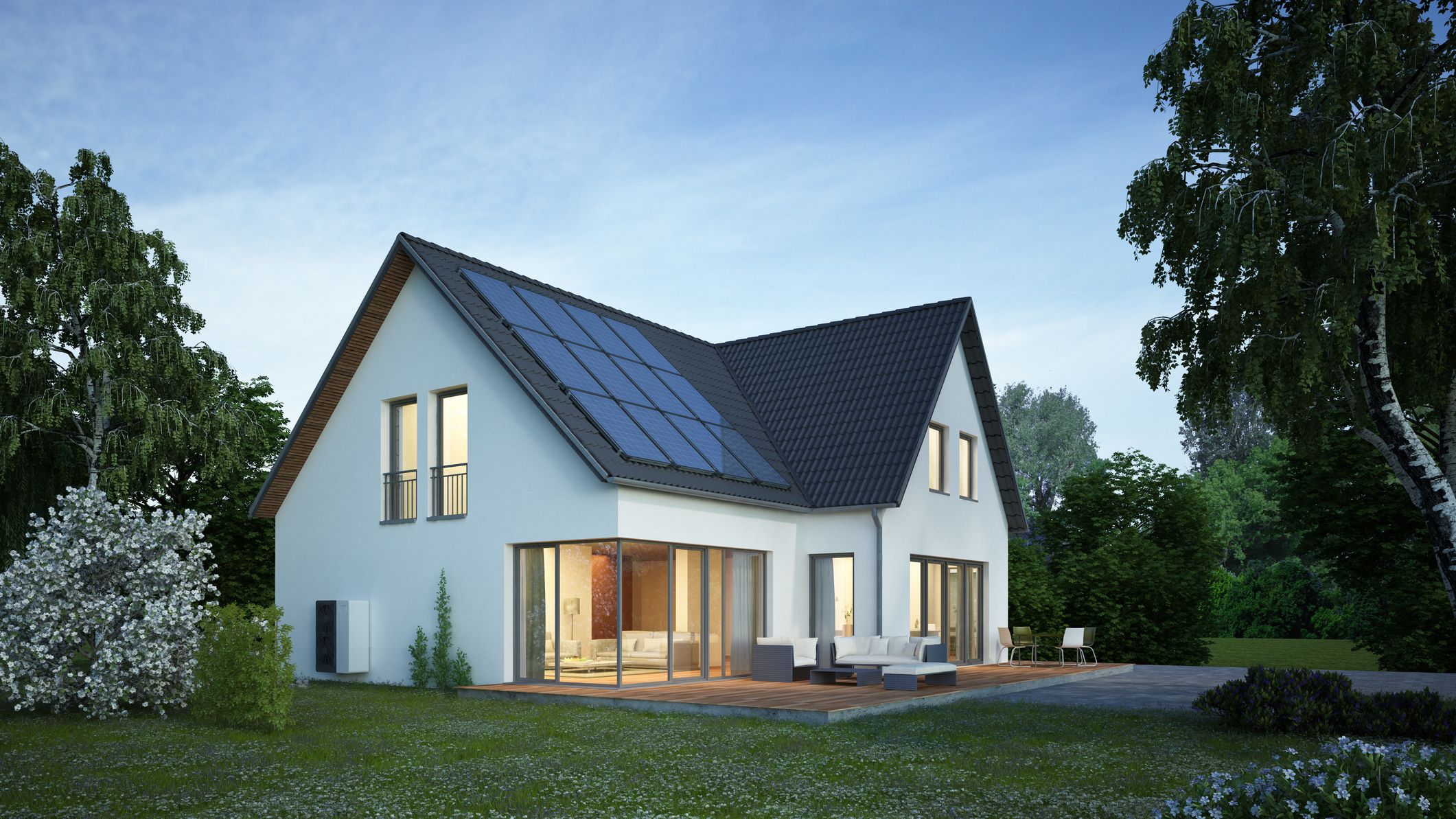 a home with solar panels and the lights on at dusk