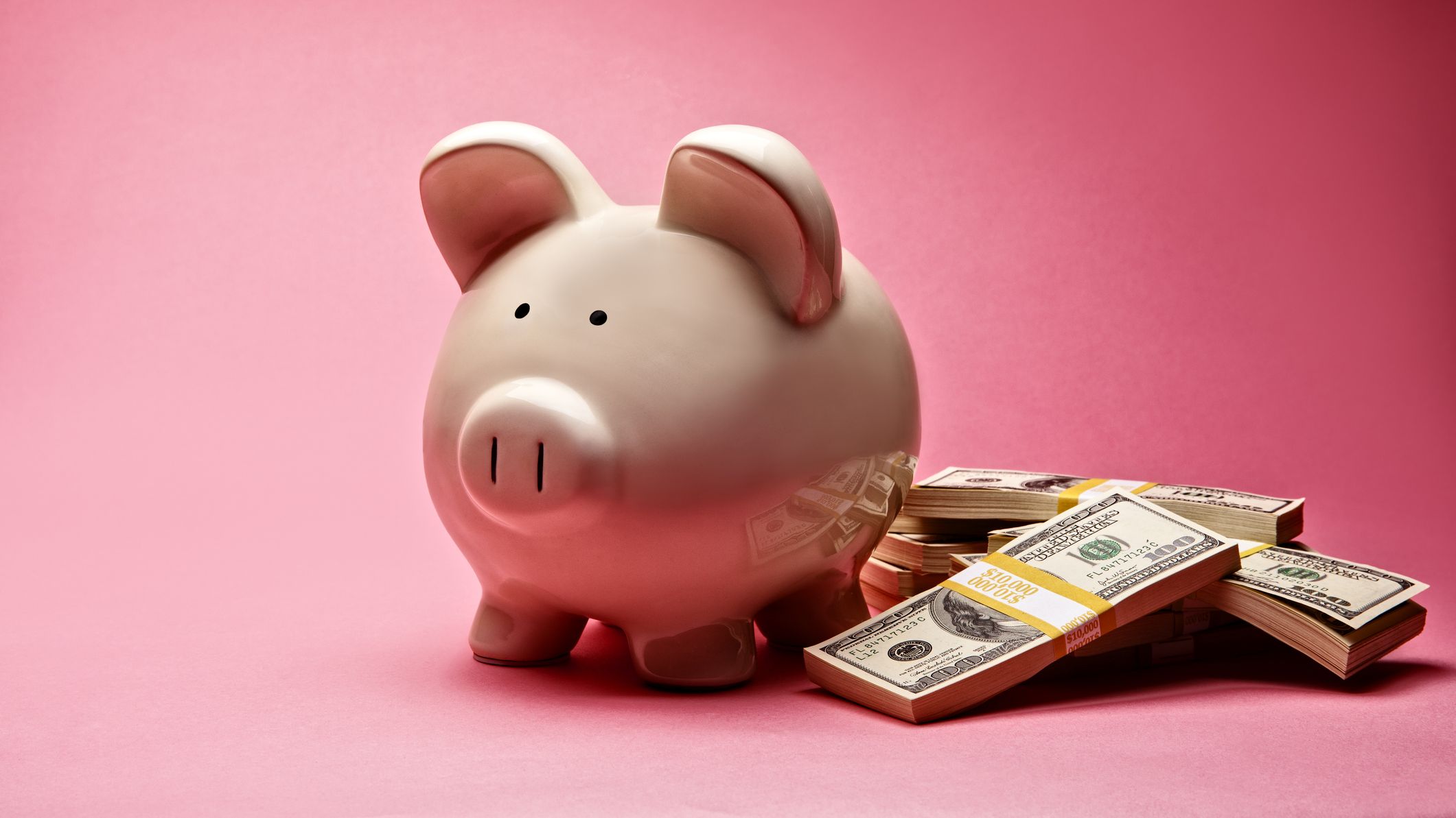 a piggy bank next to a stack of dollar bills