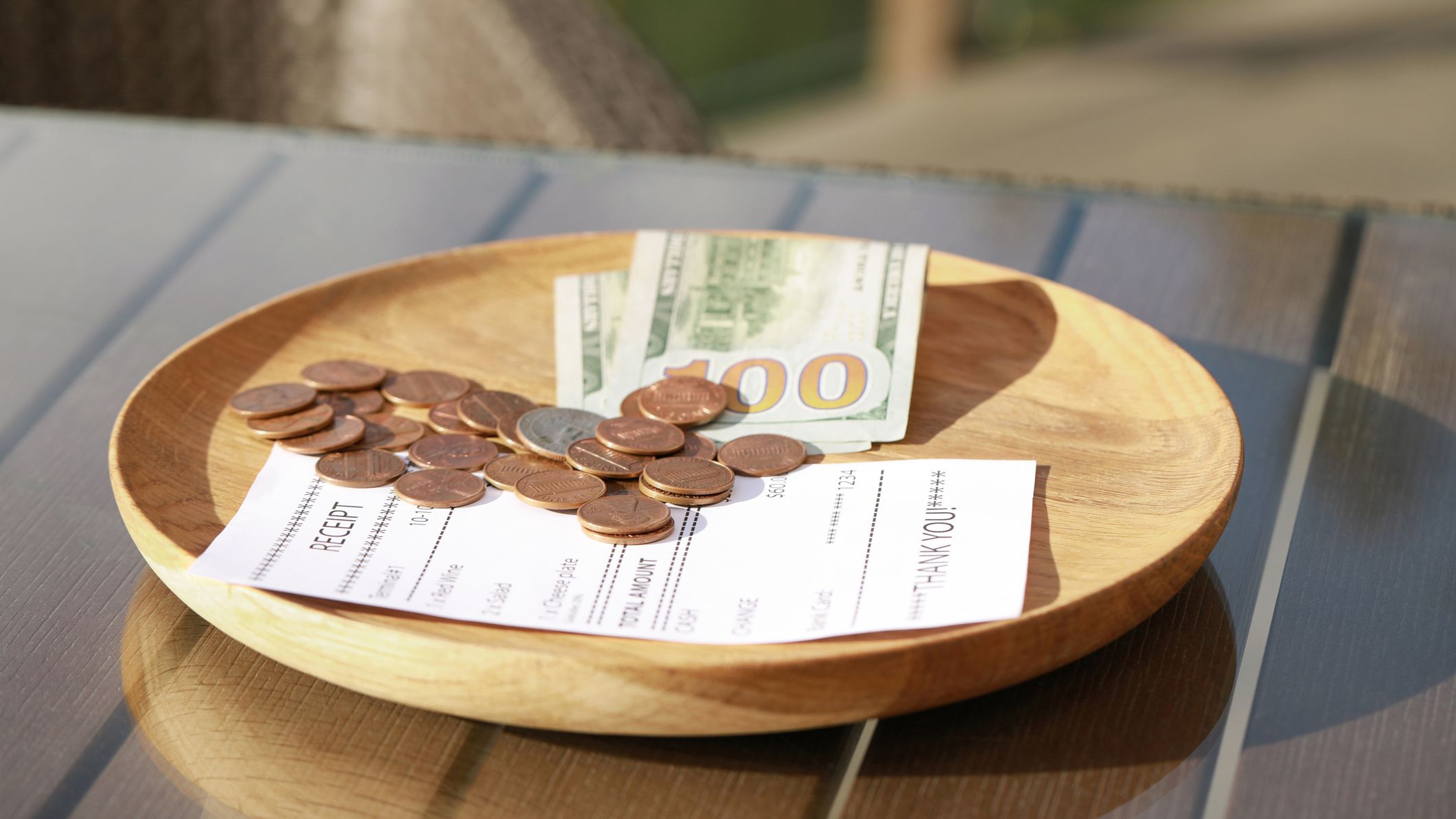 Wooden plate with payment for order and receipt on table, closeup.