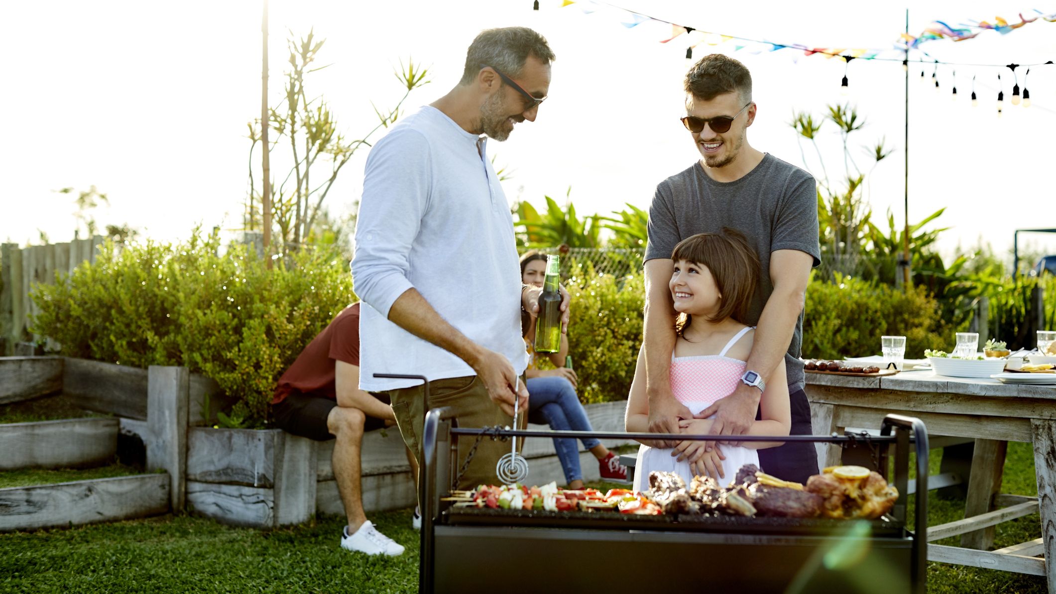 Man talking with smiling girl while preparing food on barbecue grill.