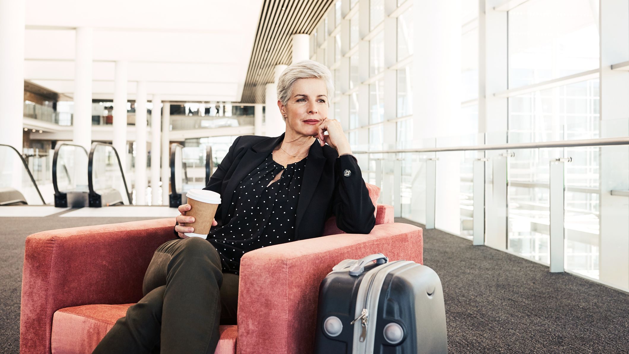 Shot of a businesswoman sitting on a chair in an airport lounge