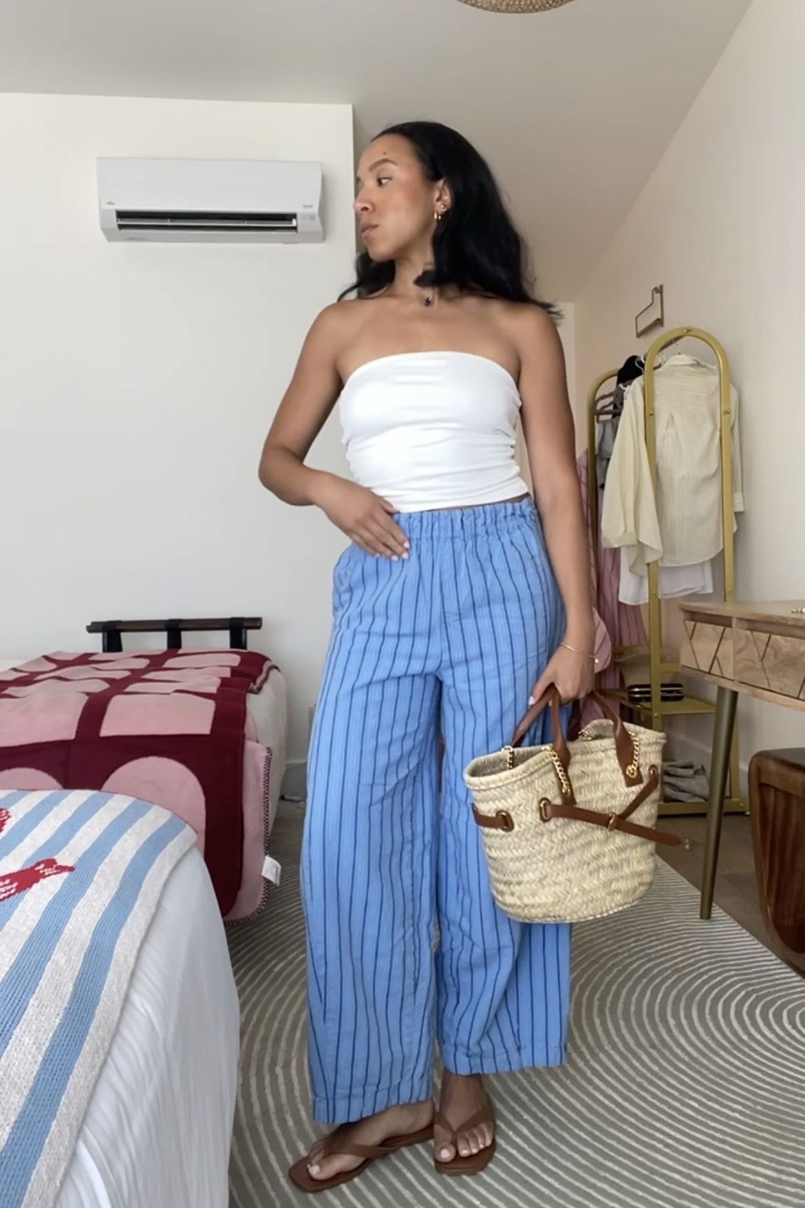 Lauren Tappan wearing striped pants, a white tube top, a raffia bag, and sandals