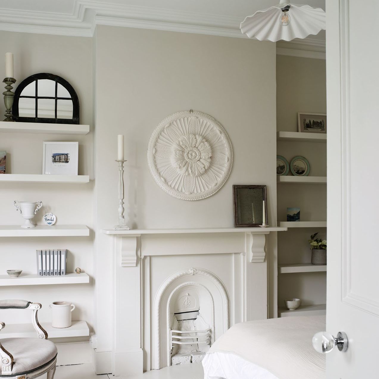 bedroom painted in shades of white with original victorian fireplace and painted floorboards