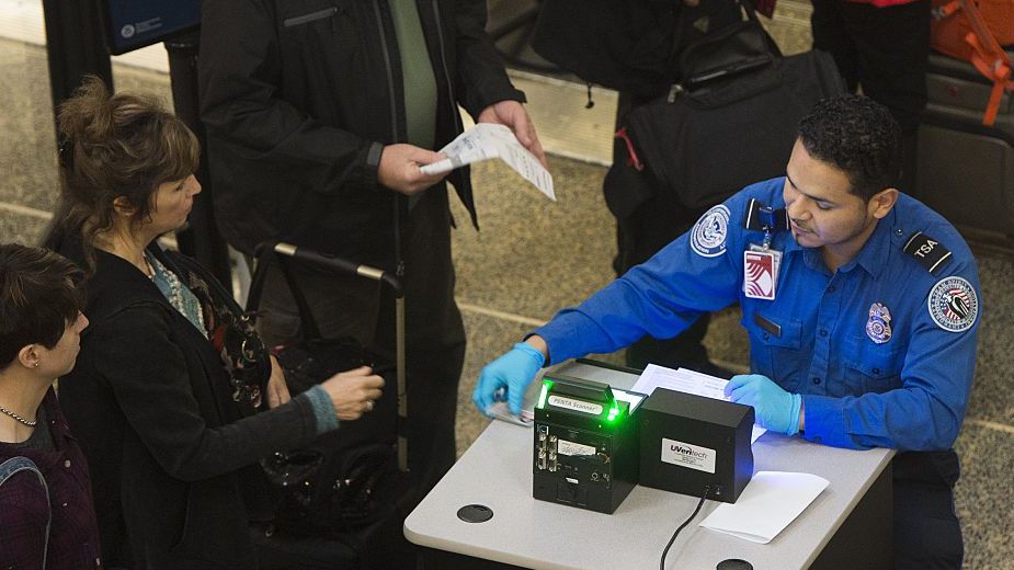A TSA Agent checks the ID's of passengers as they pass through a security checkpoint on the way to their flights at Reagan National Airport in Arlington, Virginia,