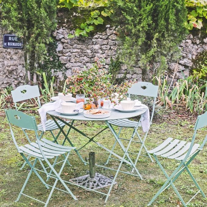 green garden bistro set, the table laid for breakfast, in a walled garden