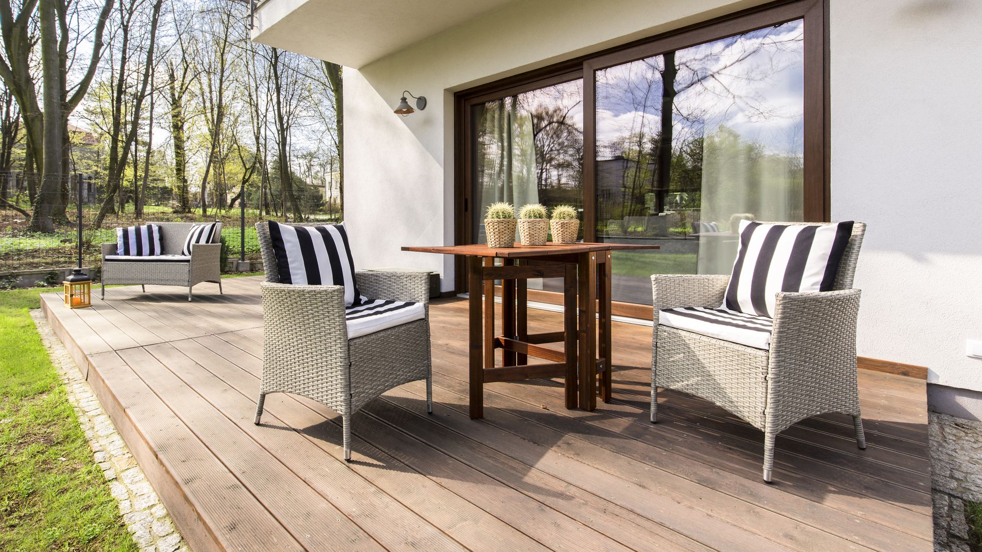 Big wooden cozy porch with chairs and coffee table in the back of big residence