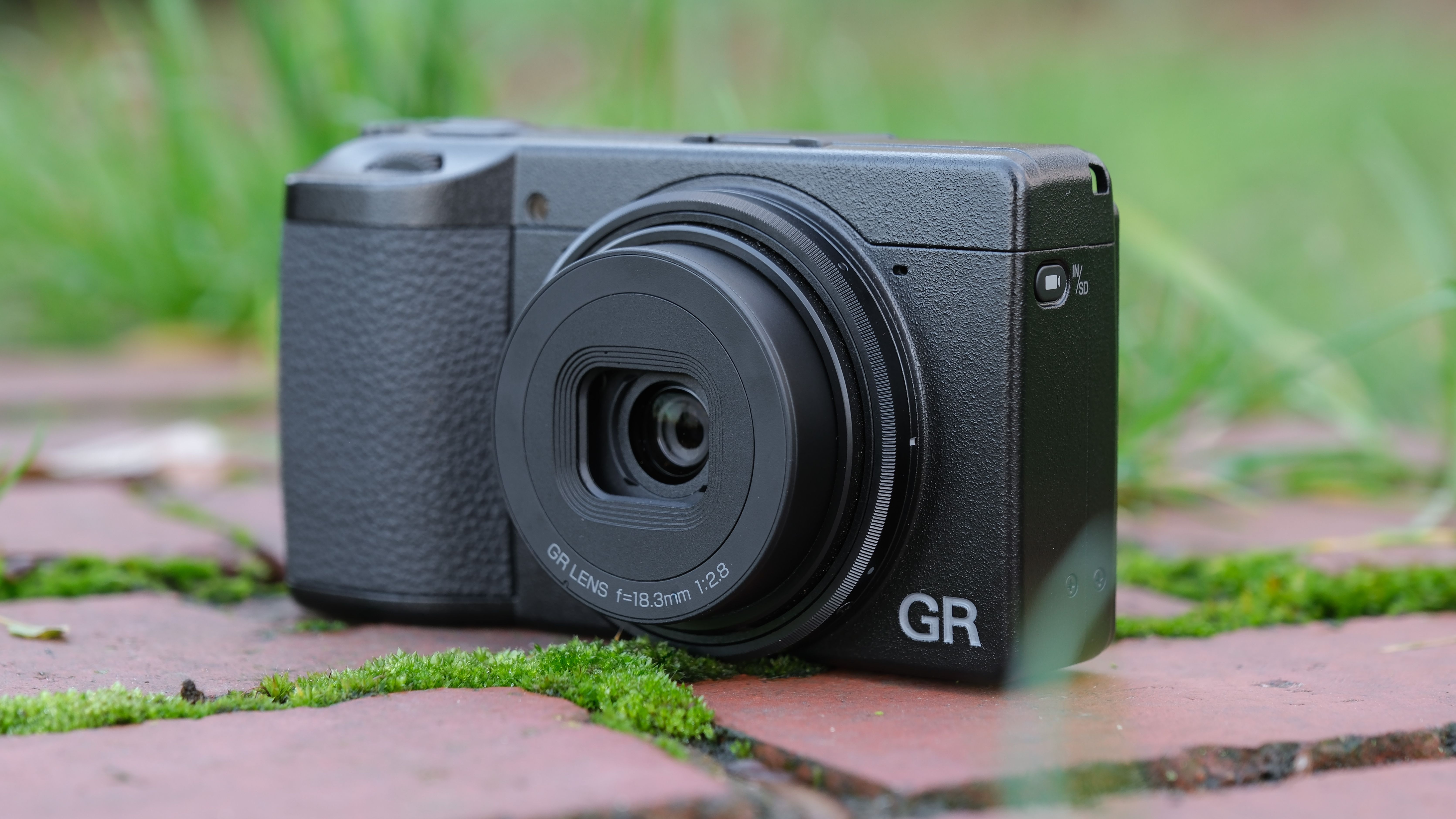 Ricoh GR IV compact camera on a brick wall