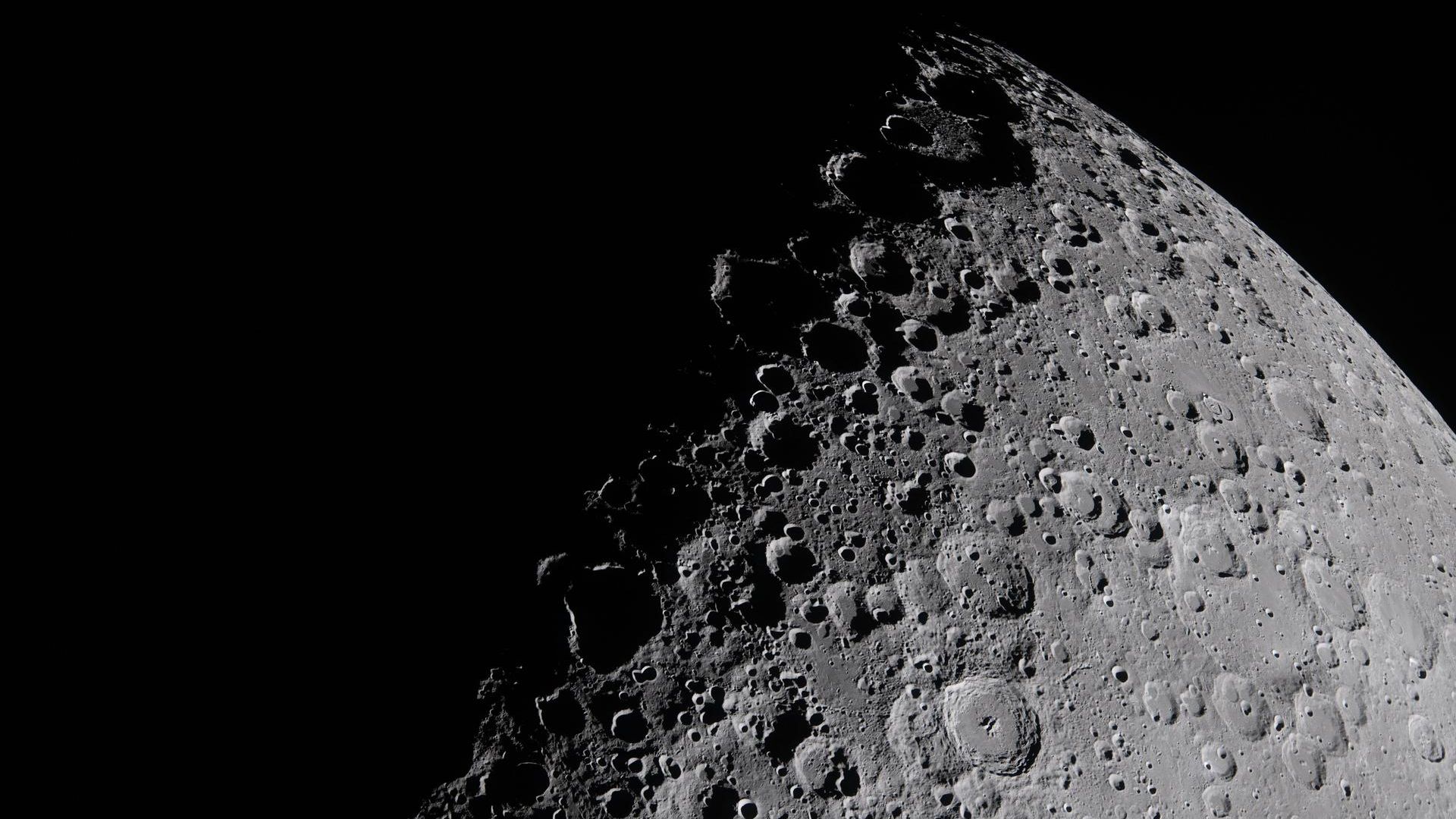 A half-shadowed view of the lunar surface featuring prominent craters.