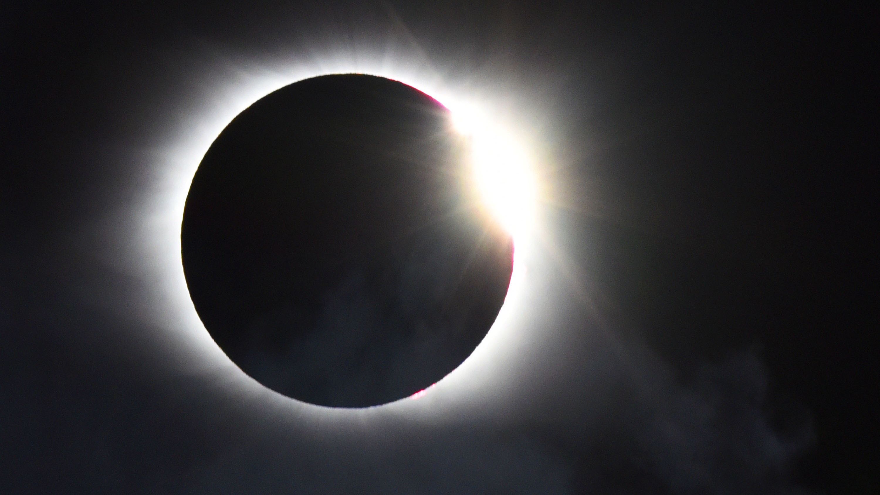 A photo of the &amp;quot;diamong ring&amp;quot; effect, captured as the last sliver of the sun's surface peeks out around the moon during a total solar eclipse in a black sky.