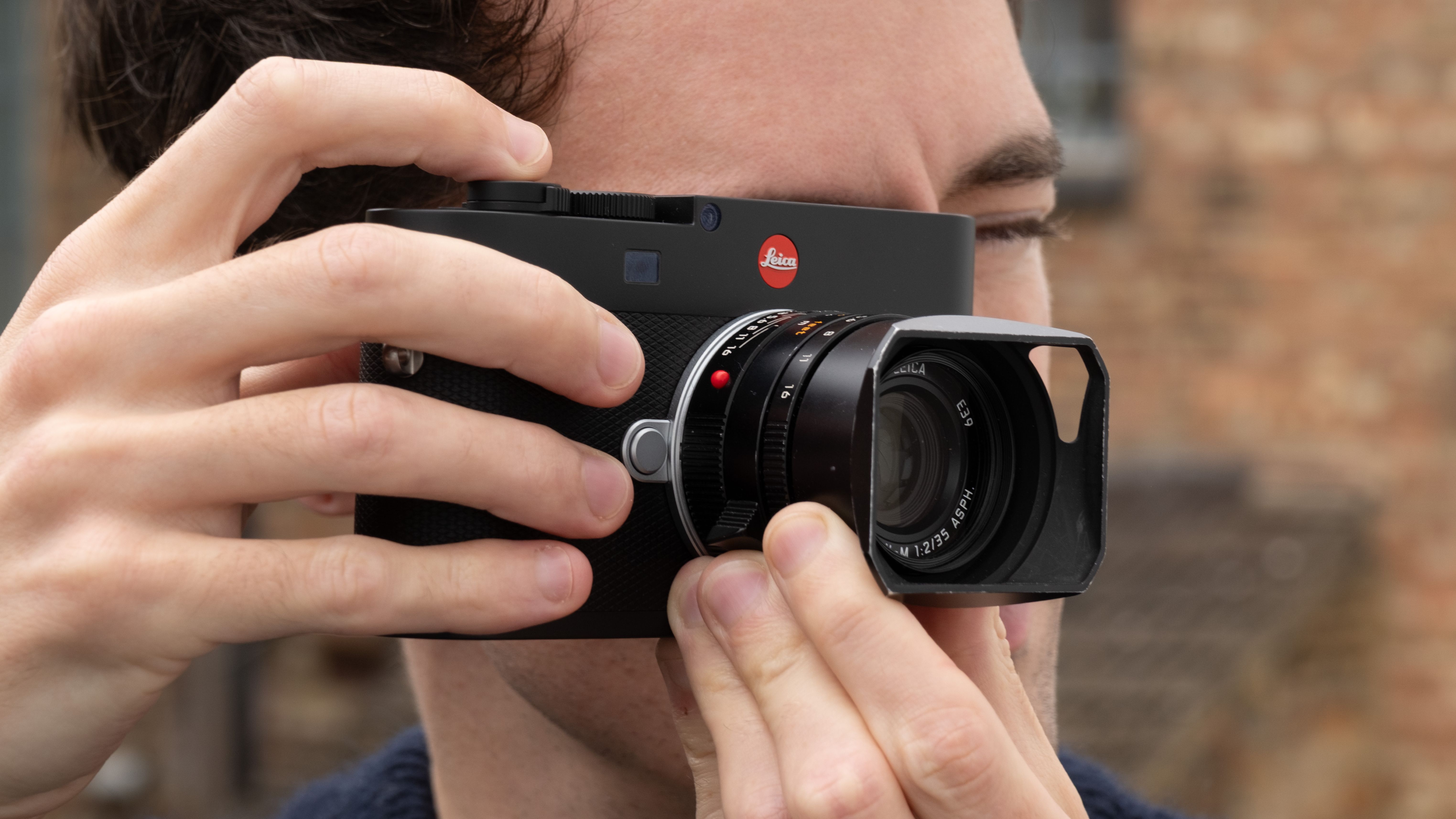Leica M EV1 digital camera with lens attached held up to a person's face