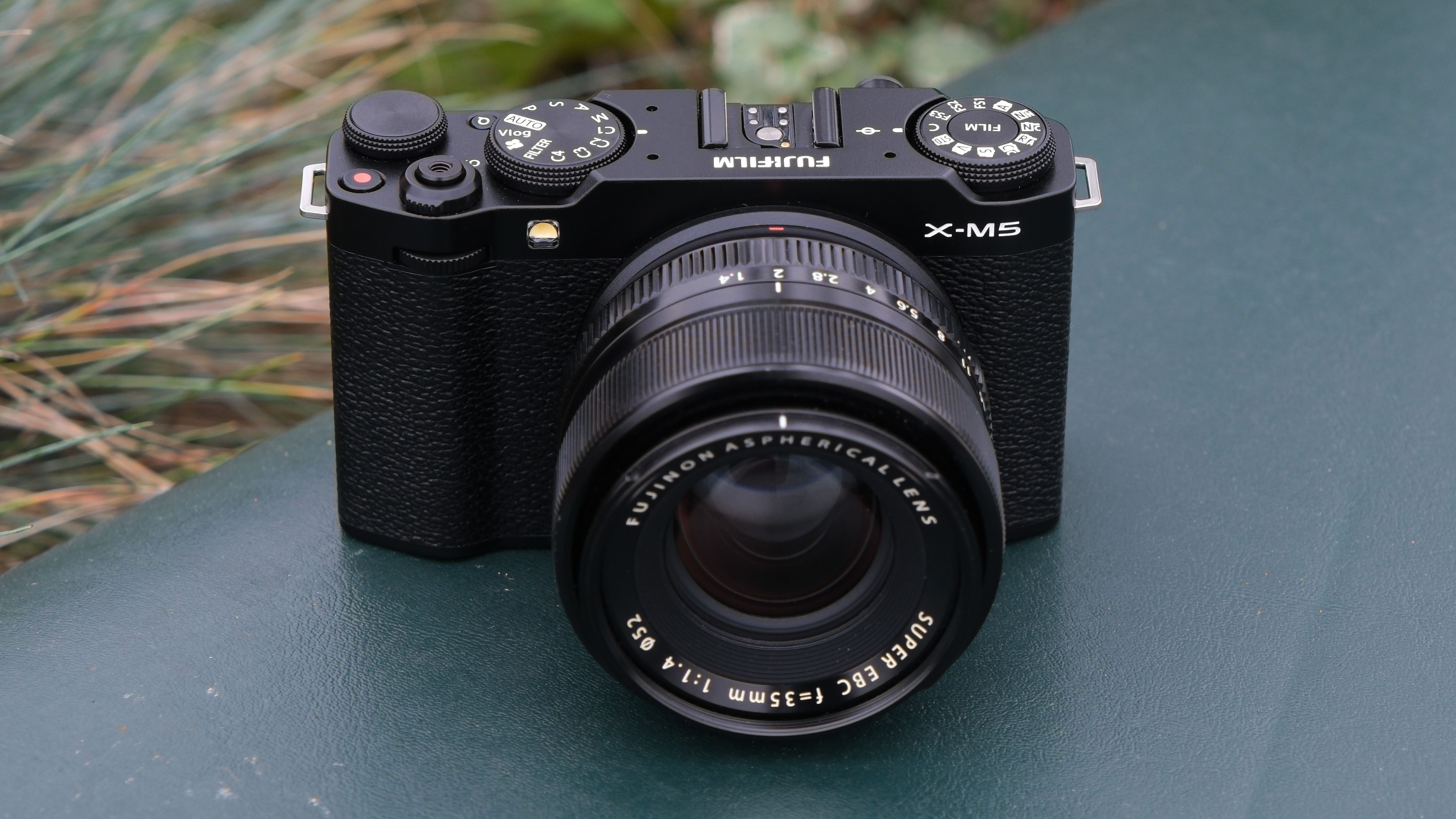 Fujifilm X-M5 camera with a Fujifilm 35mm lens attached on a green surface