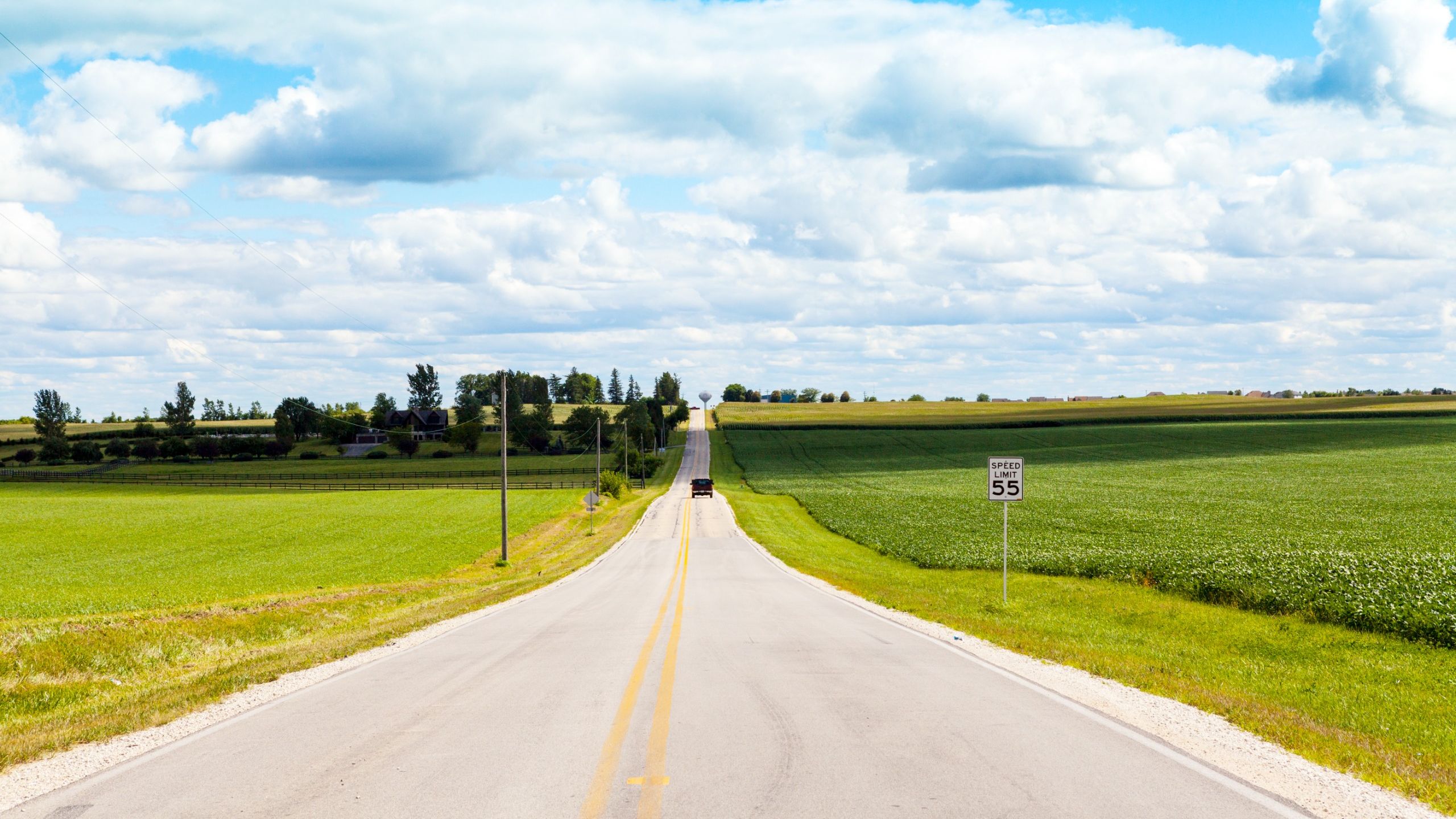 An empty, straight road going through corn fields in Iowa.