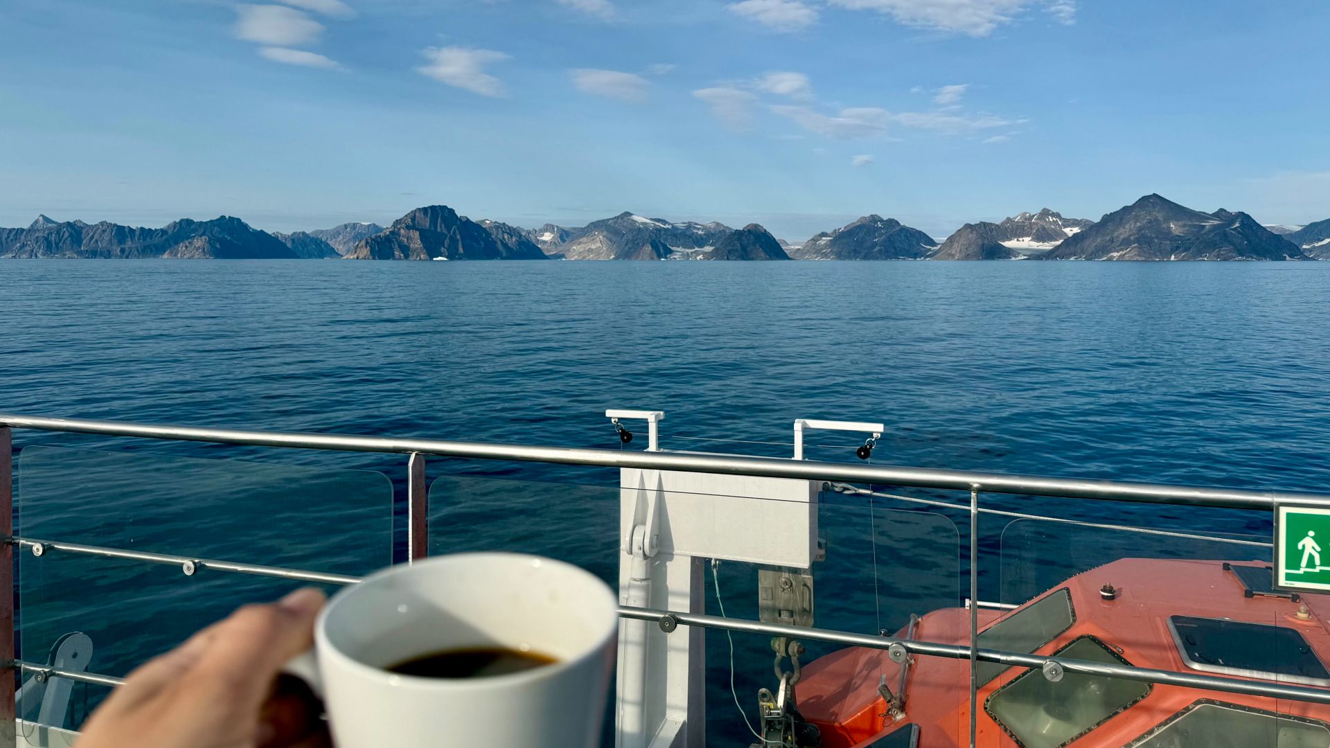a cup of coffee in the foreground and then a large body of water and distant mountains