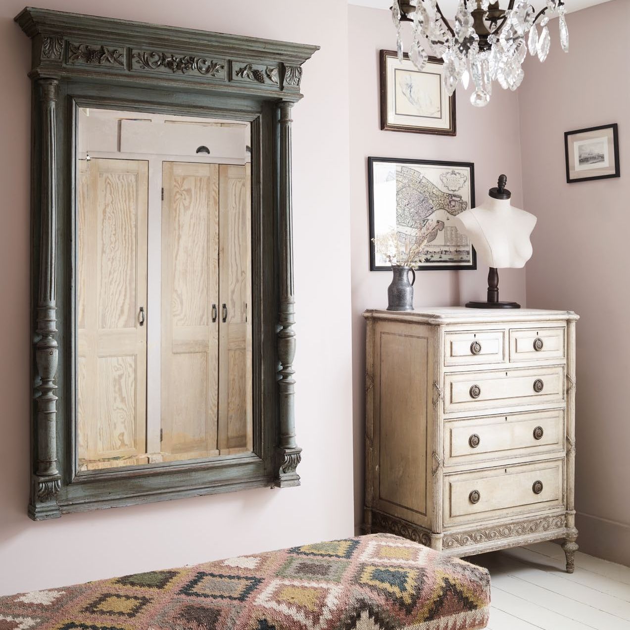 dressing room with large antique wall mirror, pink walls, ottoman and chest of drawers