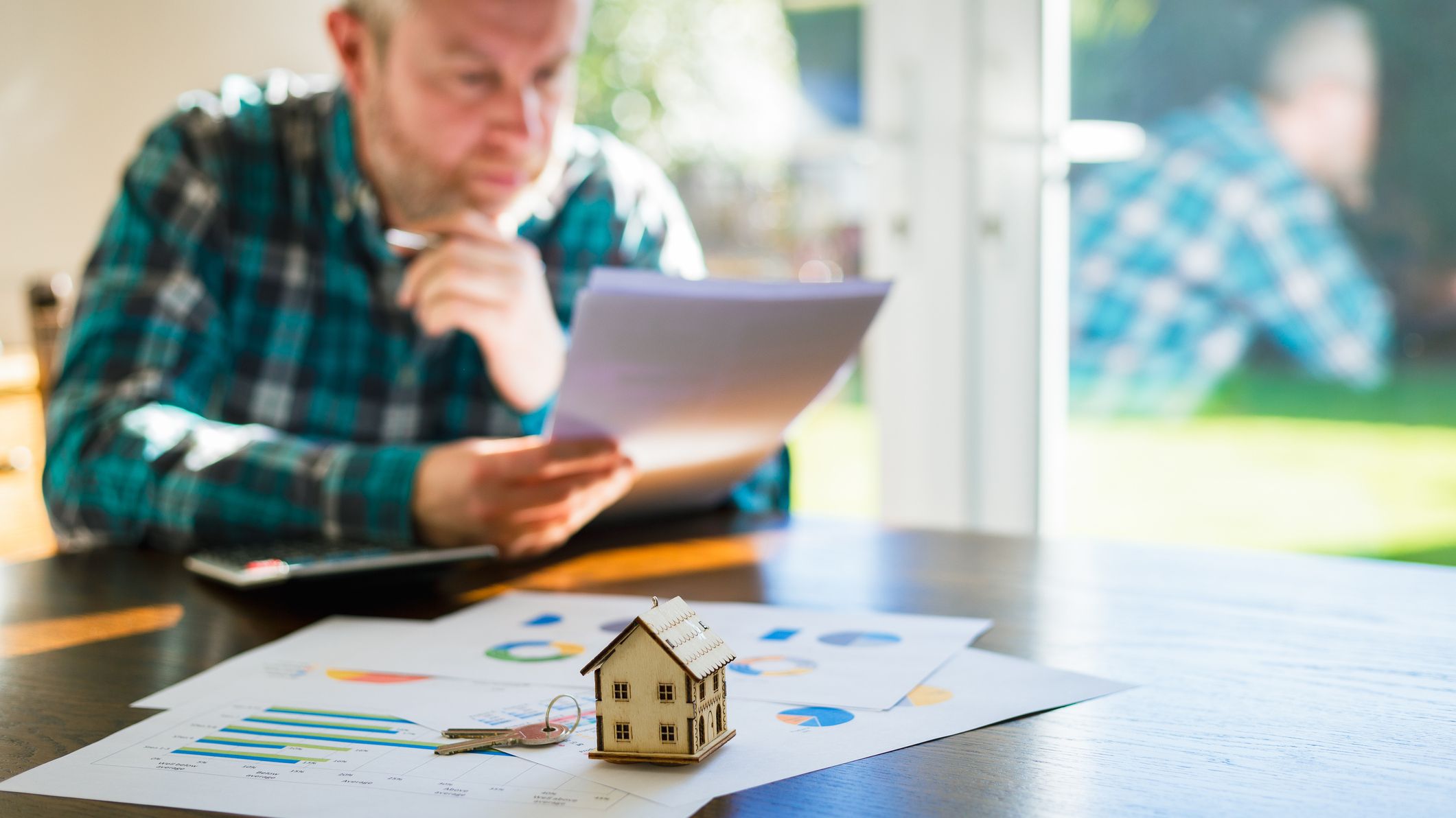 A man is looking at documents pertaining to a house sale agreement.
