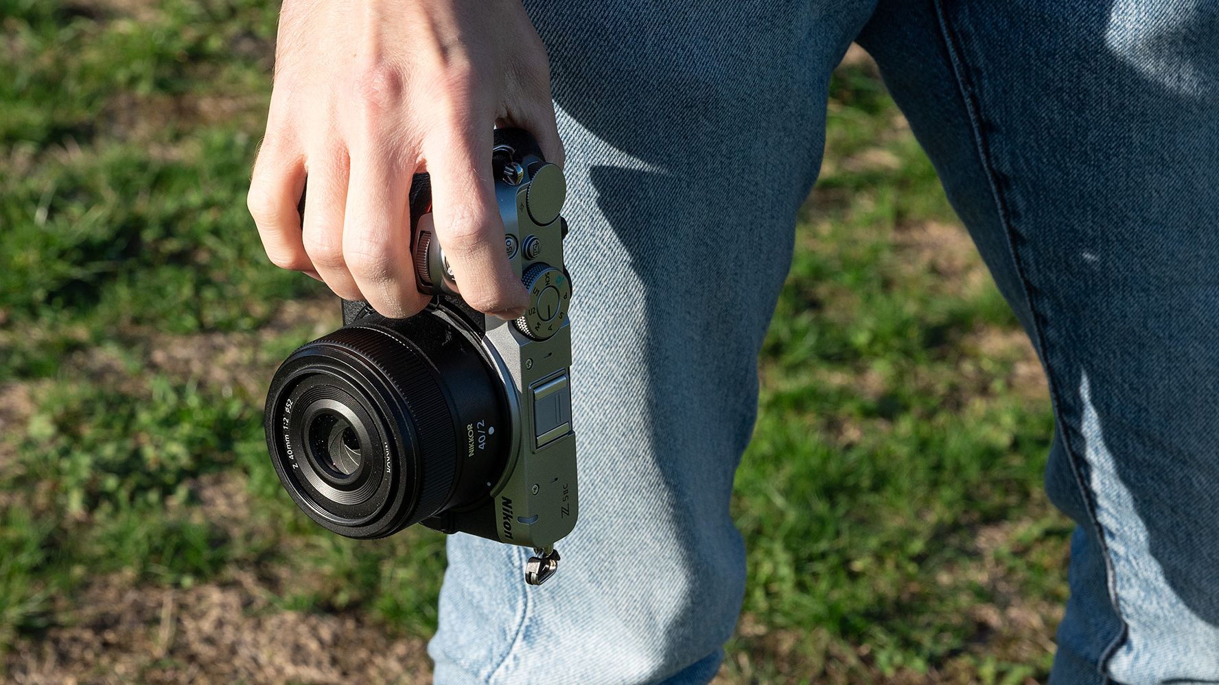 Mike Harris wearing a t-shirt and jeans holding the Nikon Z5IIC on a green background