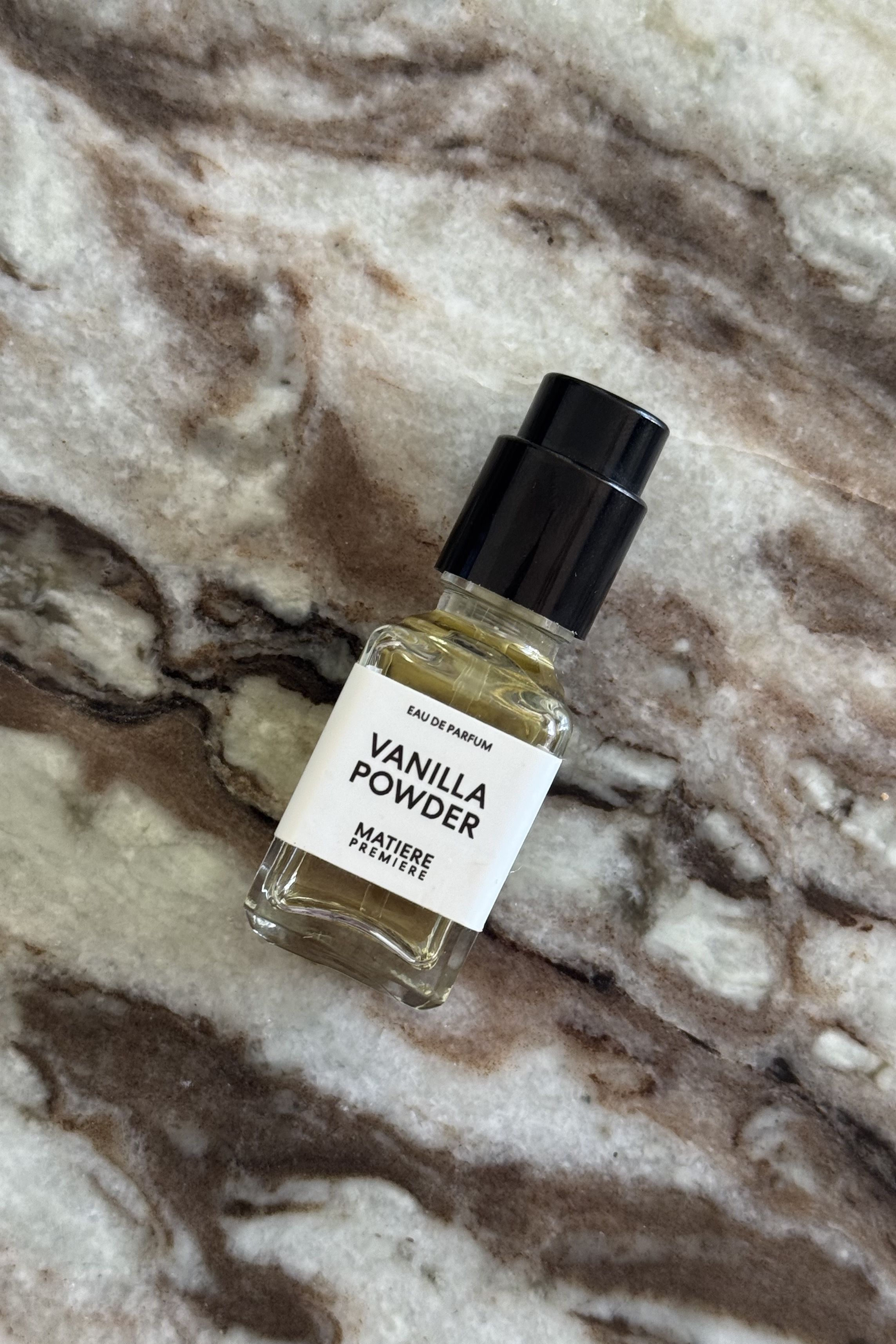 A mini bottle of Vanilla Powder eau de parfum on a marble background