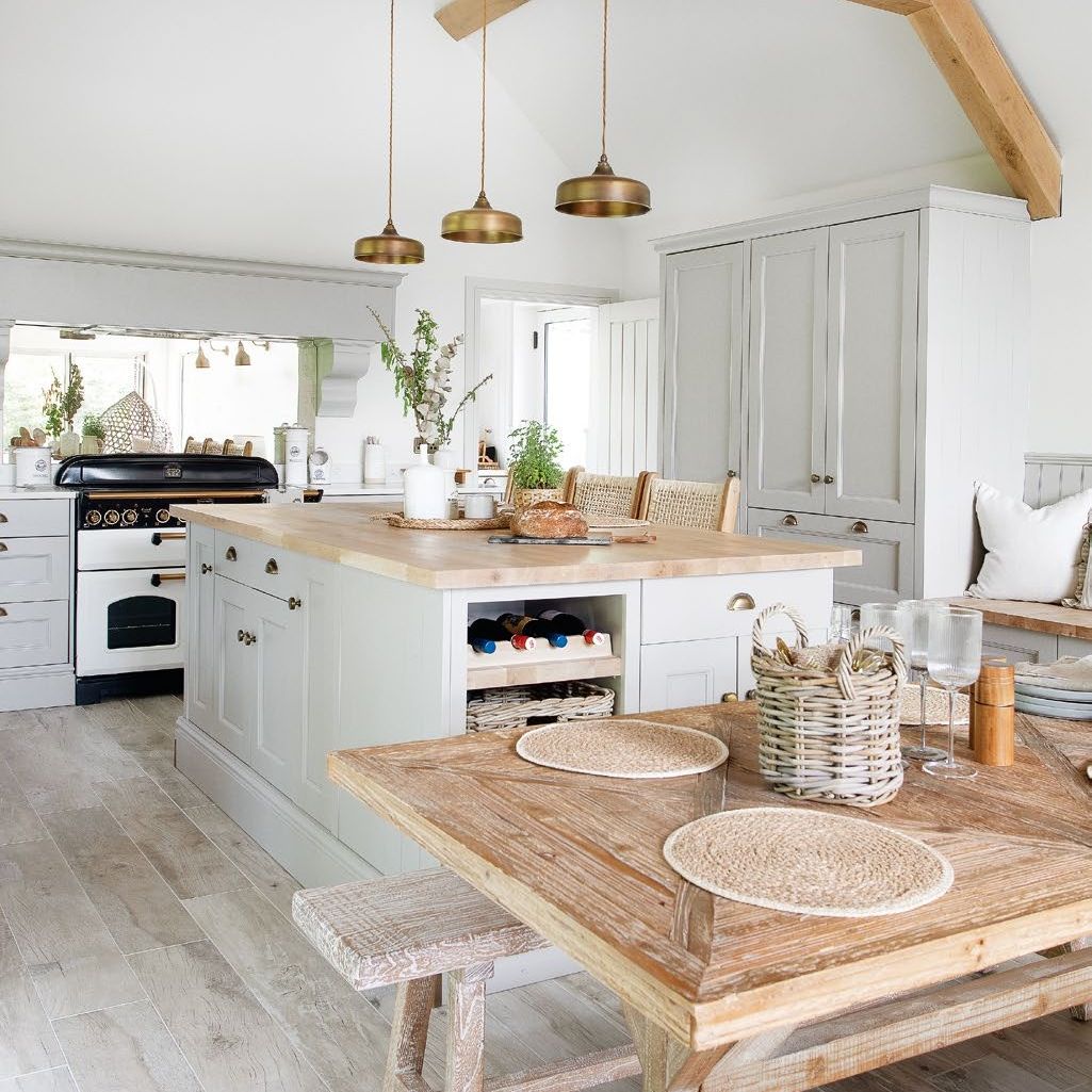 White kitchen with wooden beams, wooden table, brass pendant lights