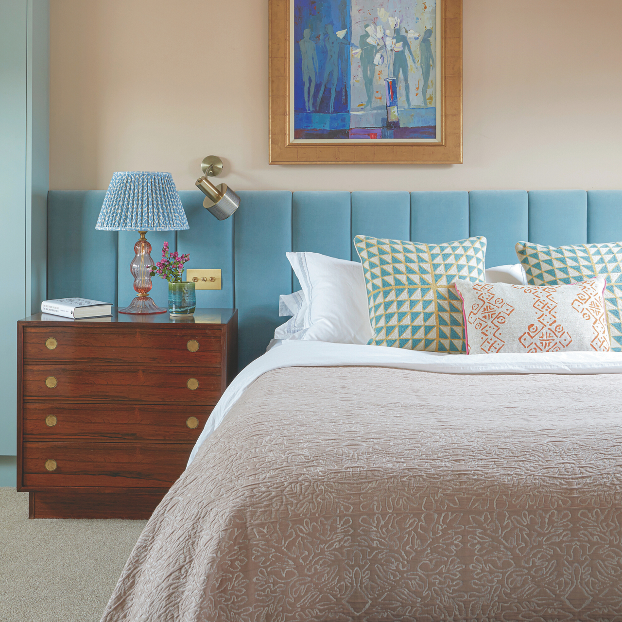 a bedroom with a large bed with pillows, a light blue headboard, and a wood side table