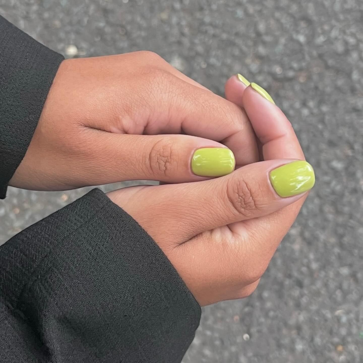 girl holding her lime green nails out and showing a little of her blazer