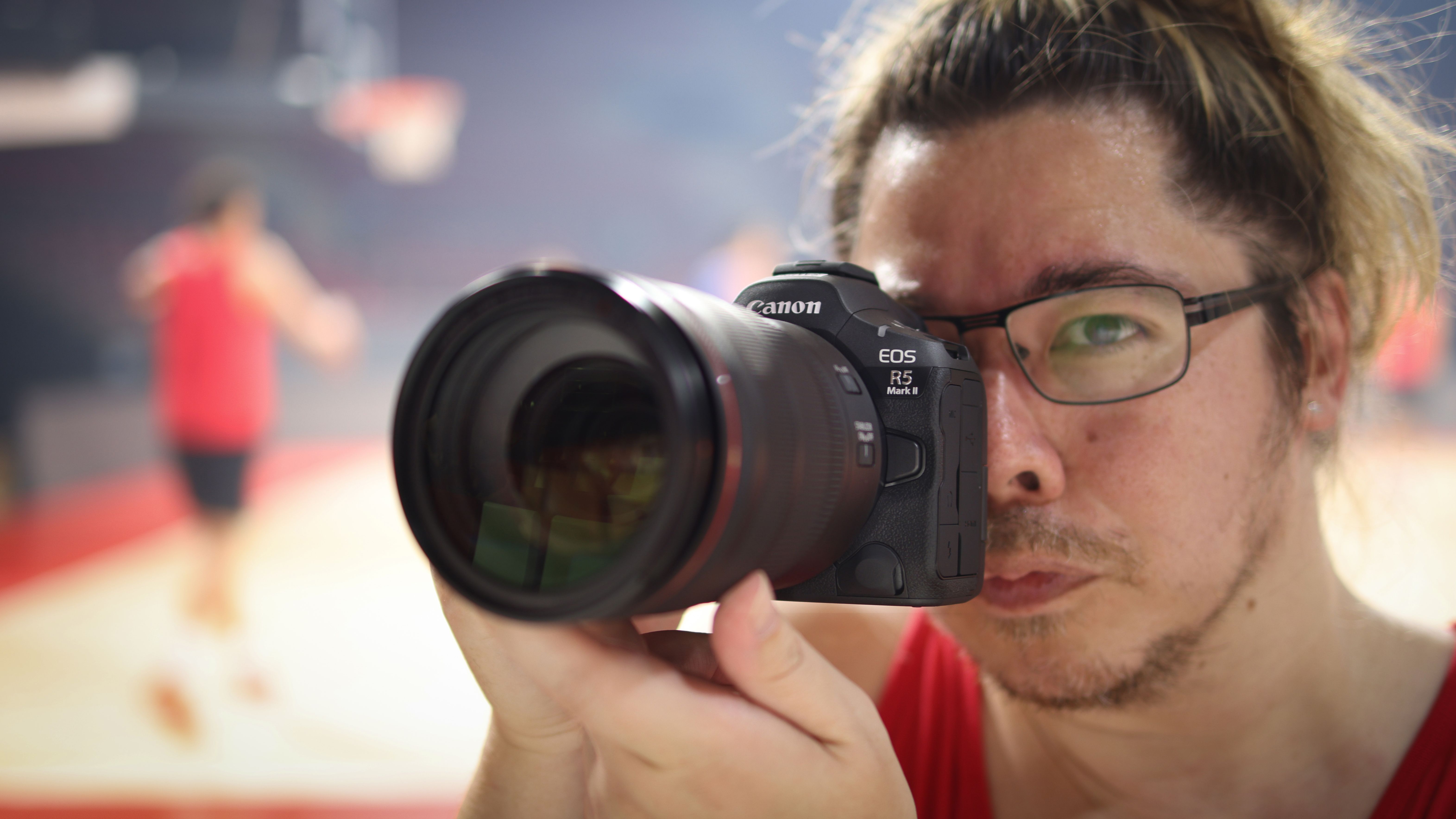 Photographer James Artaius using a Canon EOS R5 Mark II in front of a basketball game