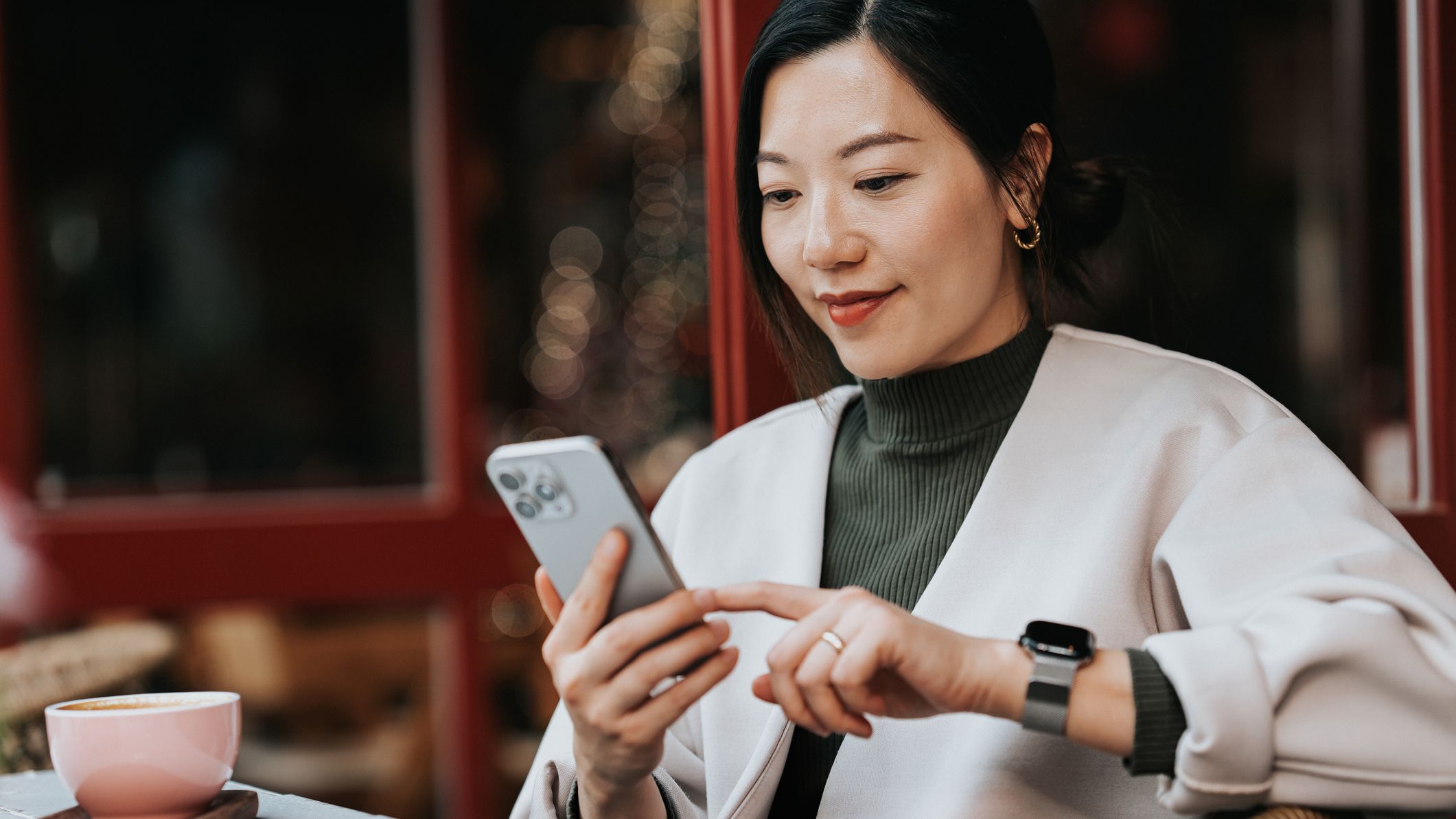 a woman scrolls her cell phone at a cafe
