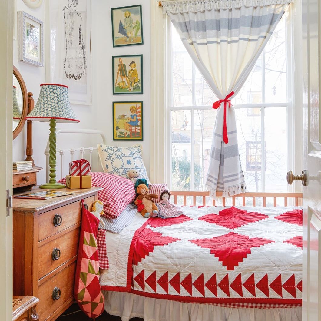 children's bedroom with patchwork quilt and cushions on bed, vintage furniture and artworks