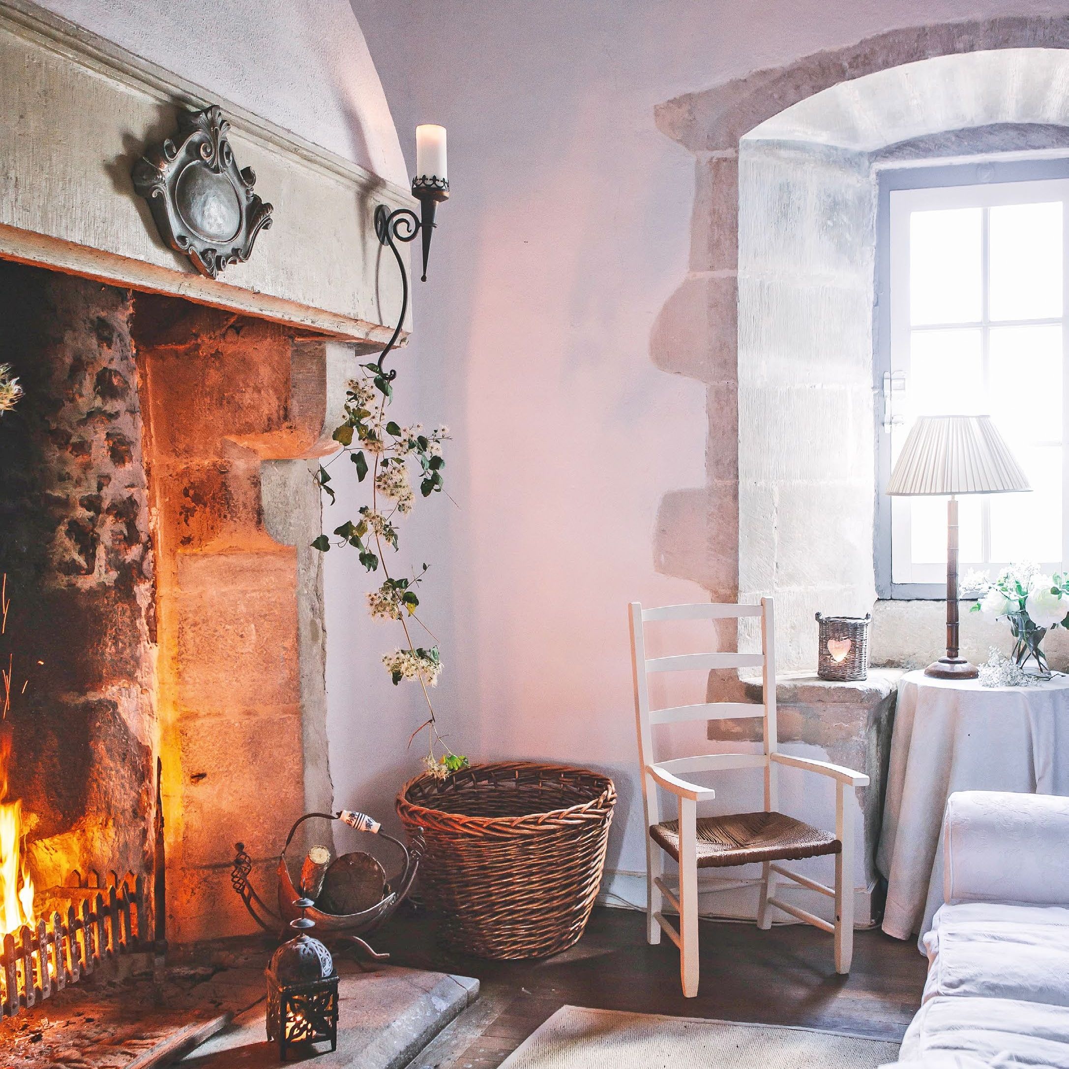Living room in a stone tower with large inglenook fireplace and stone mullion window