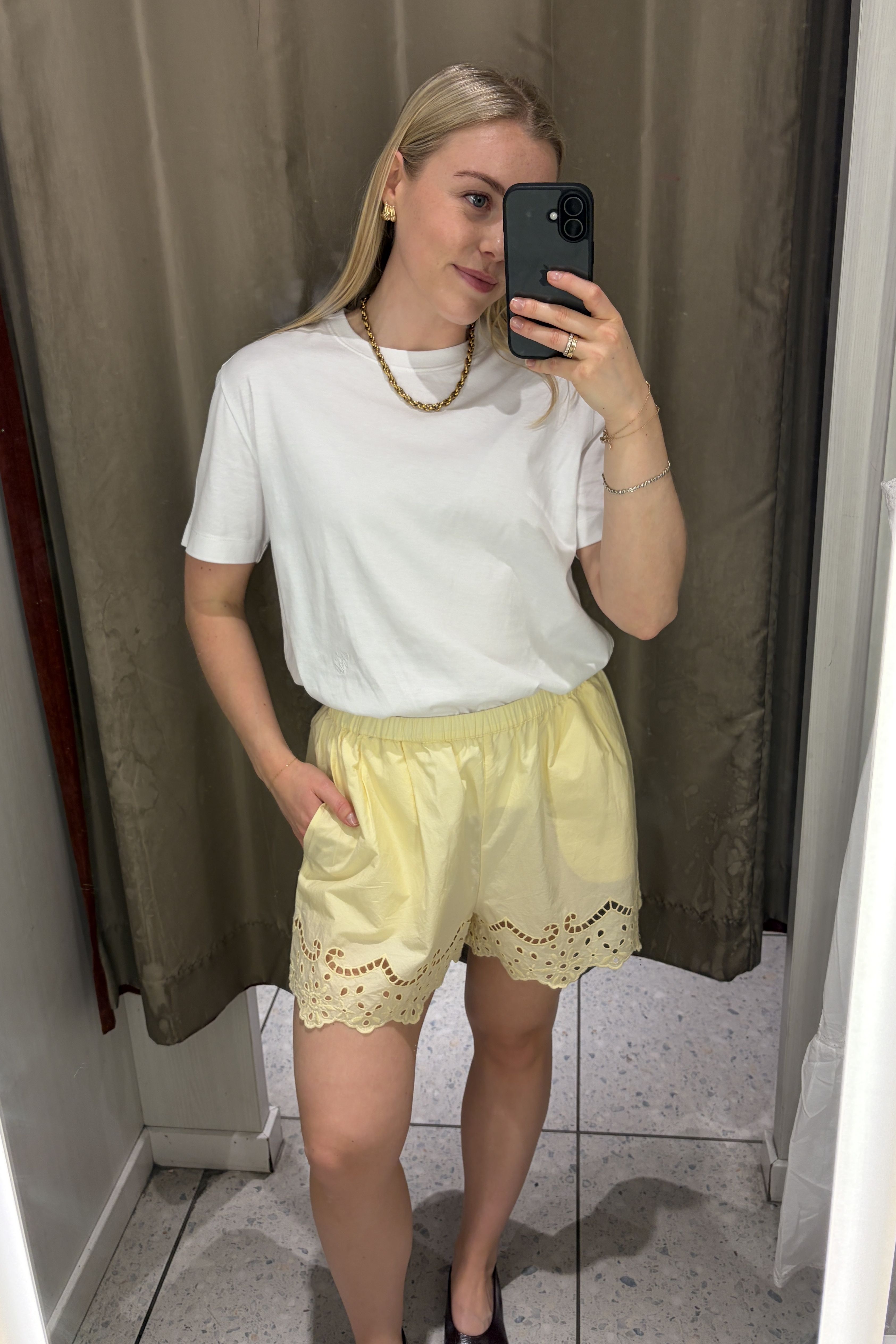 Woman wears white T-shirt, yellow broderie shorts