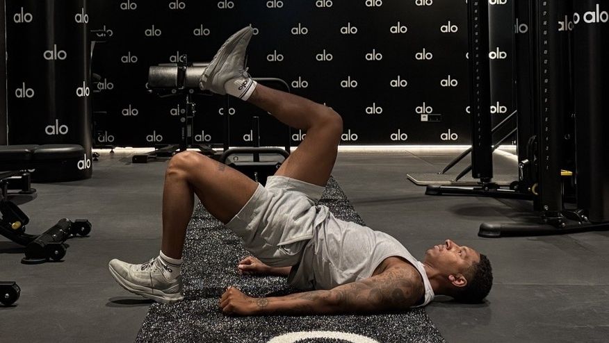 Man demonstrates glute bridge march in gym