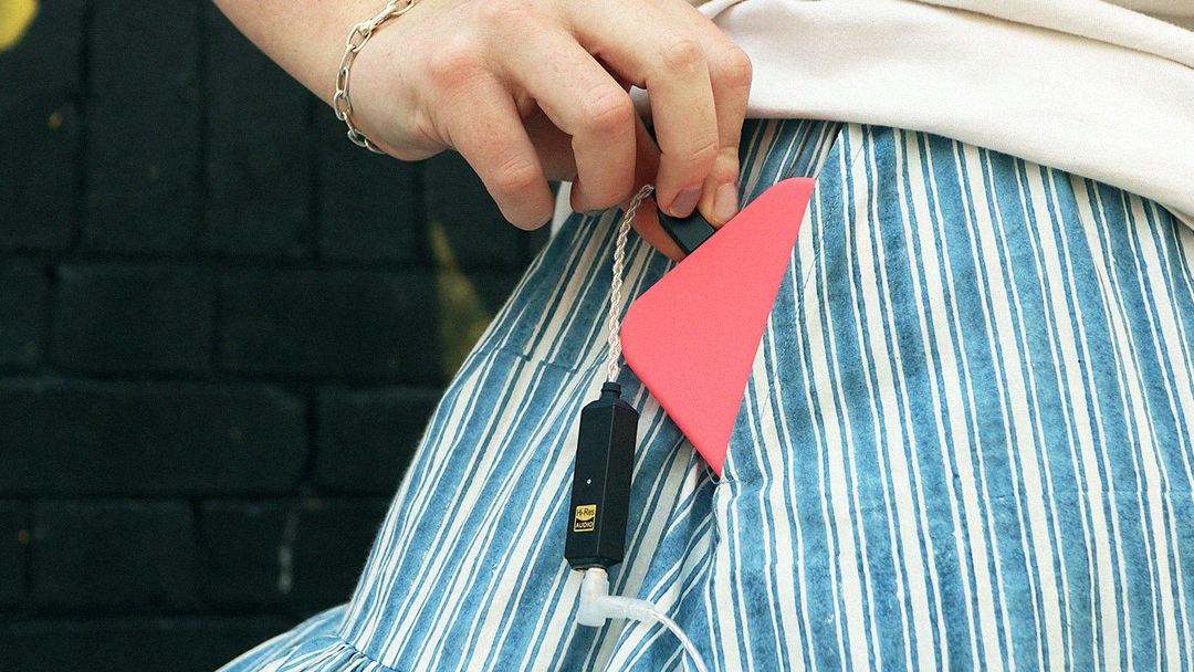 iFi Go Link 2 Max emerging from a woman's pocket, with a phone connected