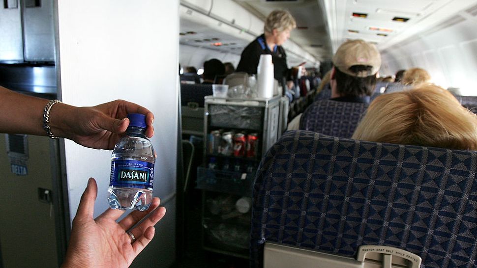 A flight attendant gives out a bottle of water to a passenger on a domestic flight in the United States.