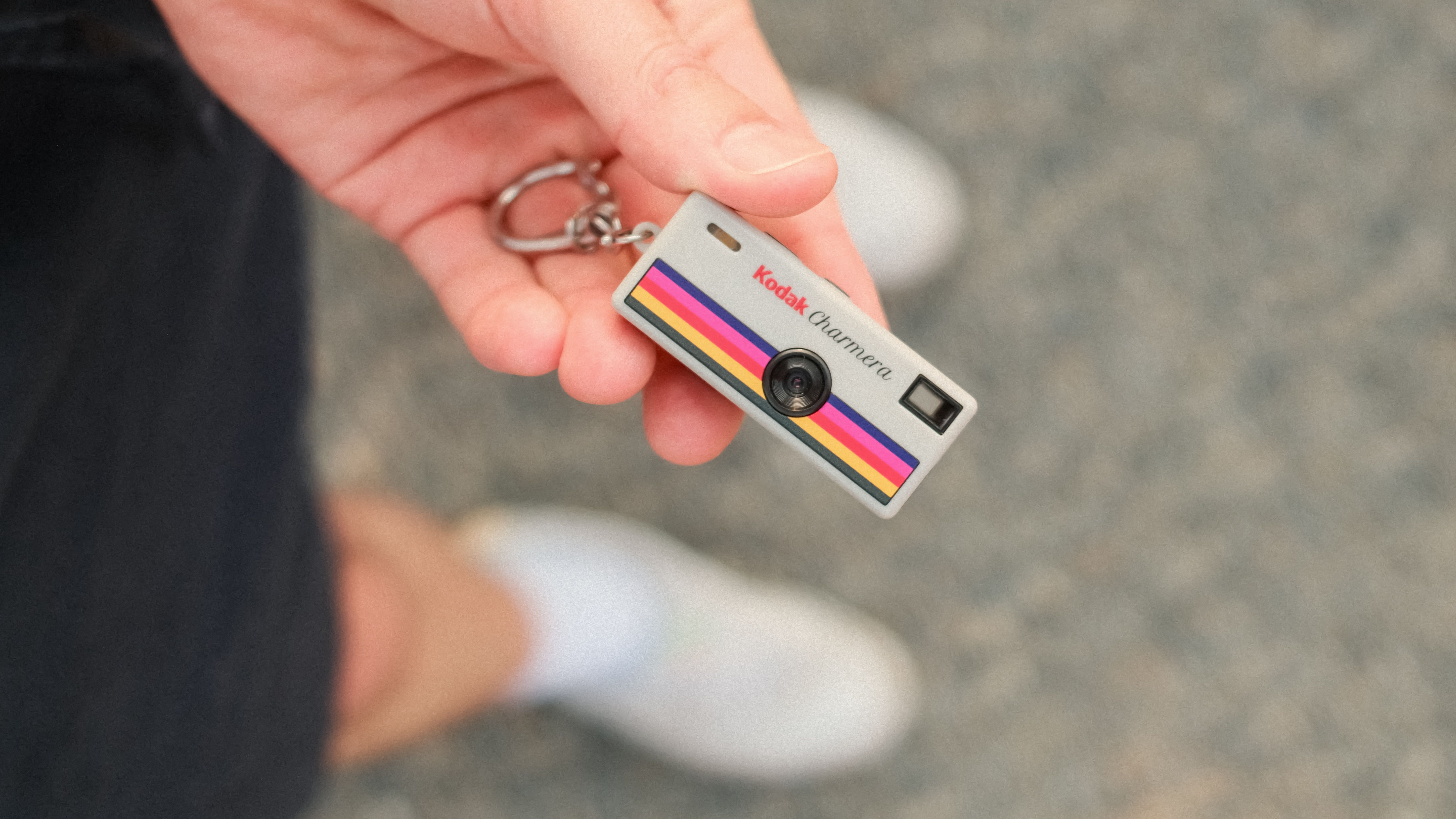 Close-up of a Kodak Charmera miniature camera keychain held in one hand.