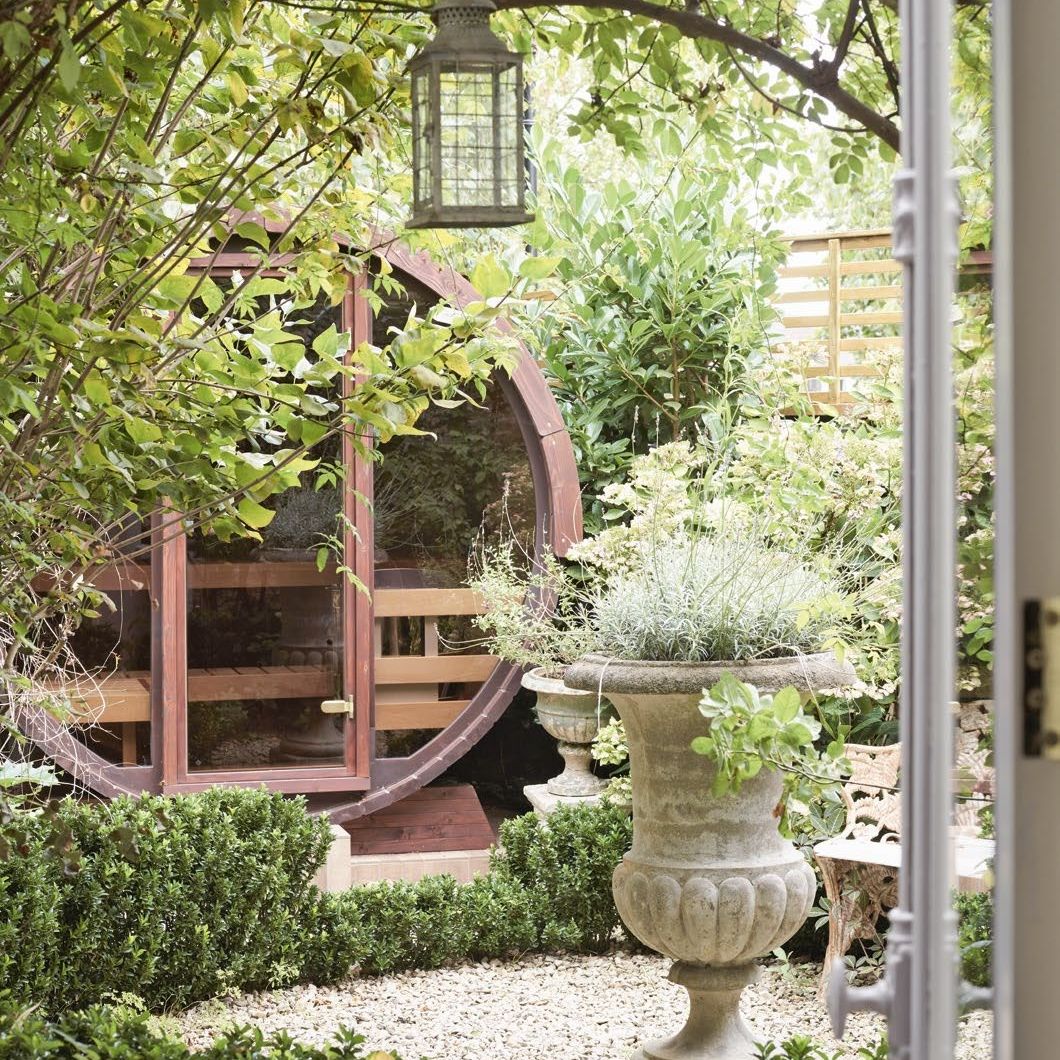 Finnish style sauna in a small courtyard garden with stone urn used as a planter