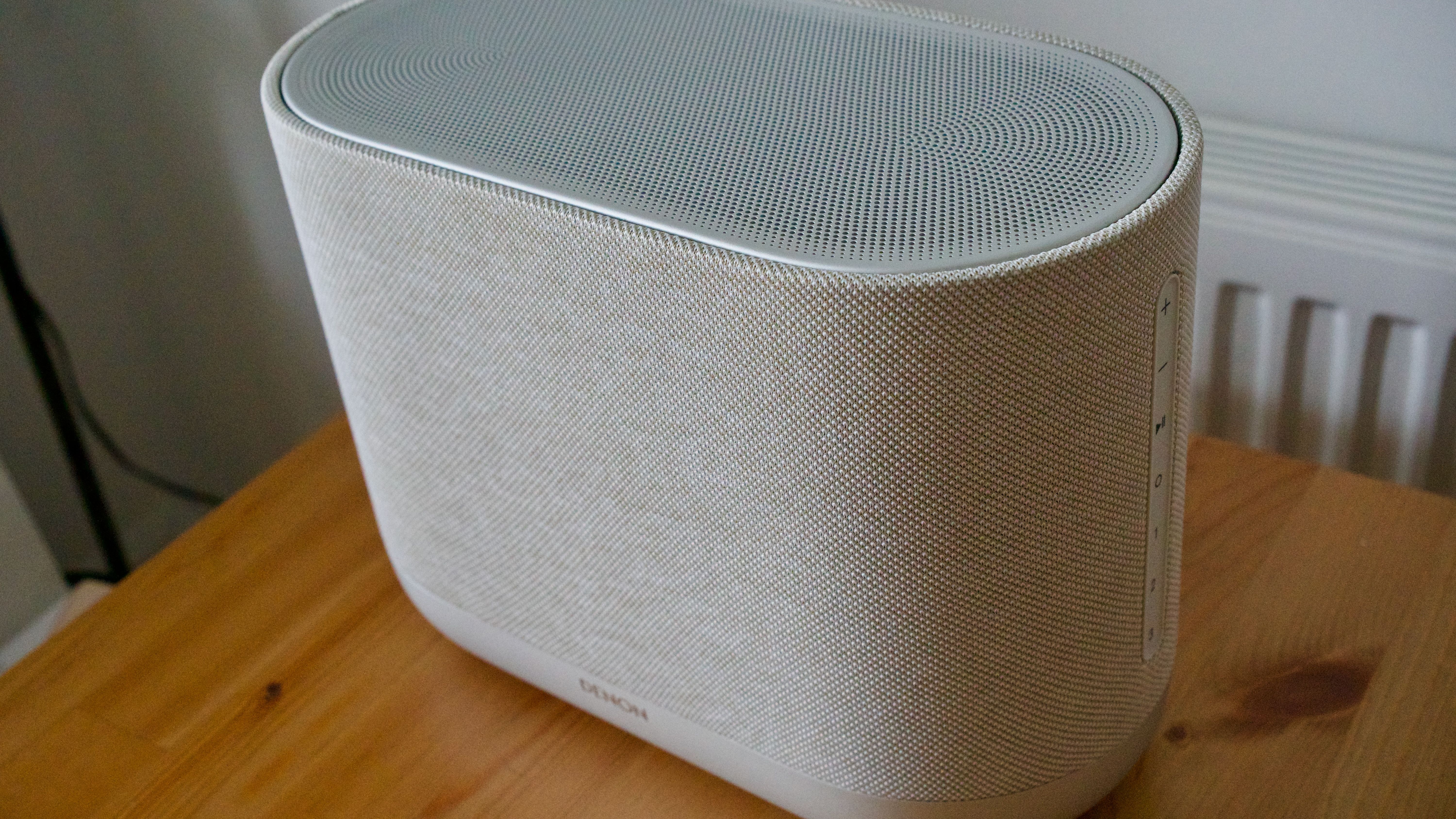 Denon Home 400 home speaker unit, on a wooden surface.
